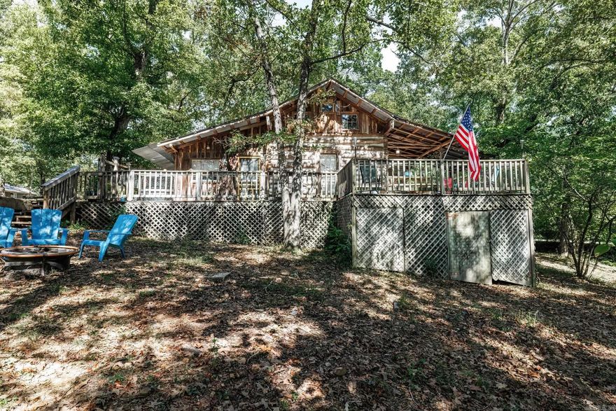 Nestled in the serene embrace of the picturesque Lake Greeson, this enchanting three-bedroom, two-bathroom cabin offers a timeless escape from the hustle and bustle of modern life. Built in the 1800s, this historic gem exudes rustic charm while providing all the modern comforts you desire. Only 30 minutes away from Crater of Diamonds and Daisy State Park.   Stepping through the threshold, you'll be greeted by a warm and inviting interior, with each room thoughtfully furnished to maintain the cabin's original character. The spacious living area boasts a cozy fireplace, perfect for chilly evenings, while the fully-equipped kitchen ensures your culinary needs are met.  The three bedrooms are spacious and inviting, promising a restful night's sleep for you and your guests. Two pristine bathrooms offer convenience and comfort, ensuring everyone's needs are met.  Perhaps the highlight of this enchanting retreat is the private hot tub, where you can soak under a canopy of stars, surrounded by the tranquility of the natural world. This cabin is a turnkey opportunity, fully furnished and ready to continue its successful journey as an Airbnb, making it an exceptional investment property.