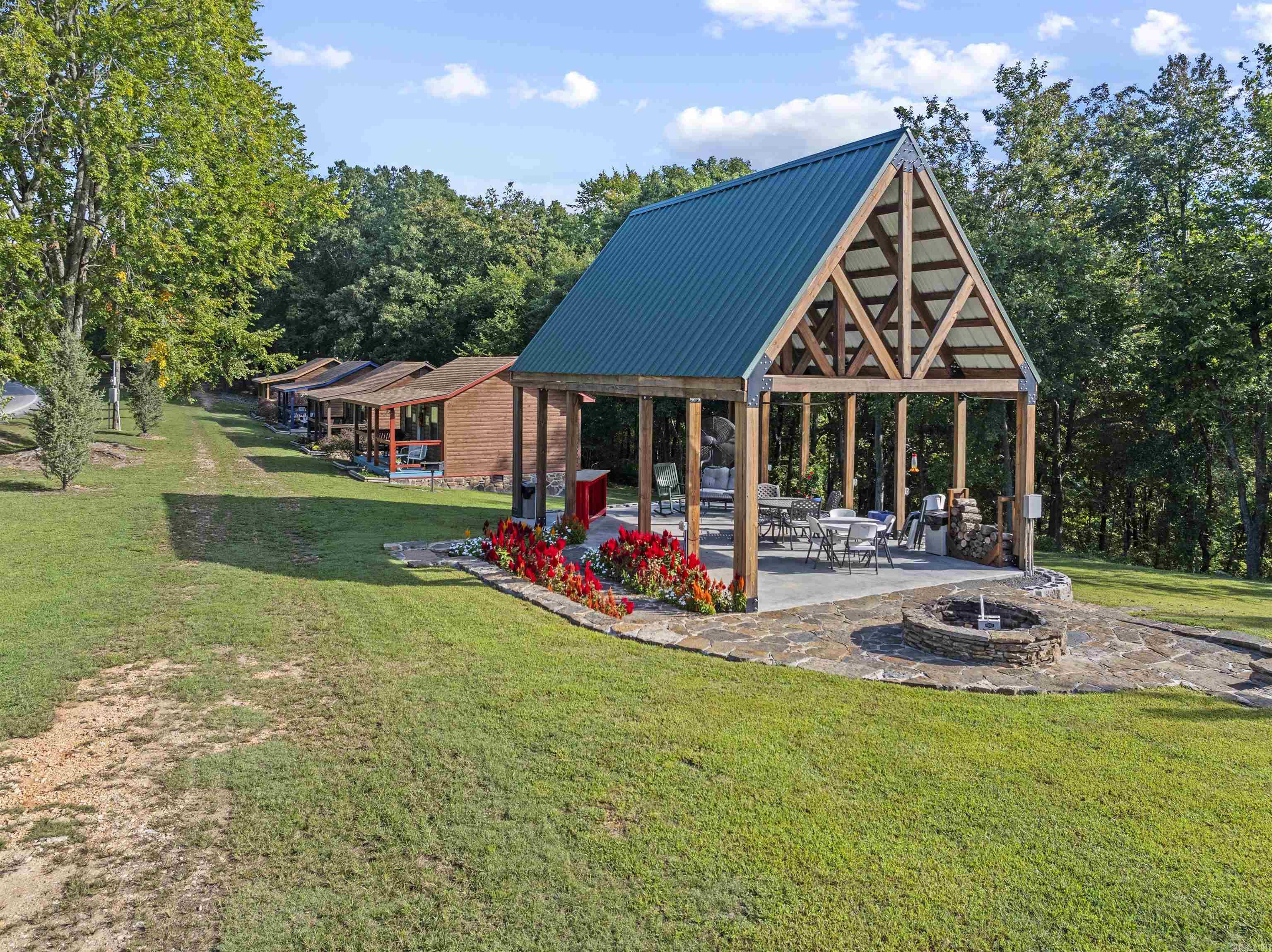 This exceptional 17-acre property near the Buffalo River is a thriving, turnkey business and a rare investment. The property includes four beautifully renovated and furnished cabins, providing guests with cozy accommodations as they explore the natural beauty of The Ozarks. The spacious main house, also, serves as an owner’s residence or a shared space for visitors, complete with a modern kitchen and expansive decks that offer breathtaking views. Perfect for gatherings, the outdoor pavilion is a favorite spot for barbecues and social events. Additionally, a 3-bedroom, 1-bath home offers additional income with minimal updates needed. The property features a shed that could easily be finished as a 7th cabin. There’s ample space to install a zip line, creating an adventure element that would boost the property's appeal as a unique destination. This property is not just a retreat but a business with room to grow. Whether you're looking to expand or continue its success, this established property.