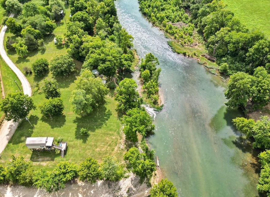 Nestled on the banks of the Spring River in Northern Arkansas, this fully furnished 2-bedroom, 1-bath waterfront cabin for sale offers the perfect blend of rustic charm and modern convenience. Situated on an 80x200 lot with 80 feet of prime river frontage, this recreational property is a dream for fishing, canoeing, and kayaking enthusiasts.  Step inside to an open floor plan featuring a spacious living room, dining area, and kitchen, all beneath a striking vaulted metal ceiling. The kitchen comes fully equipped with a stove, refrigerator, microwave, and cookware—ready for your weekend getaways. Comes completely furnished with furniture, bedding, appliances, cookware, outdoor seating, electric fireplace, washer/dryer, heaters, air conditioning unit & more!  This metal cabin has a deck plus a covered front porch. It was built above flood stage per previous flood elevation certificate & did not flood in April 2024 ARK floods  Enjoy the stunning river views of the Spring River on one side or the peaceful sights of the cattle farm behind the property. Conveniently located just 15 minutes from Hardy, AR, and a short drive to the Black River, Eleven Point River & Lake Charles.