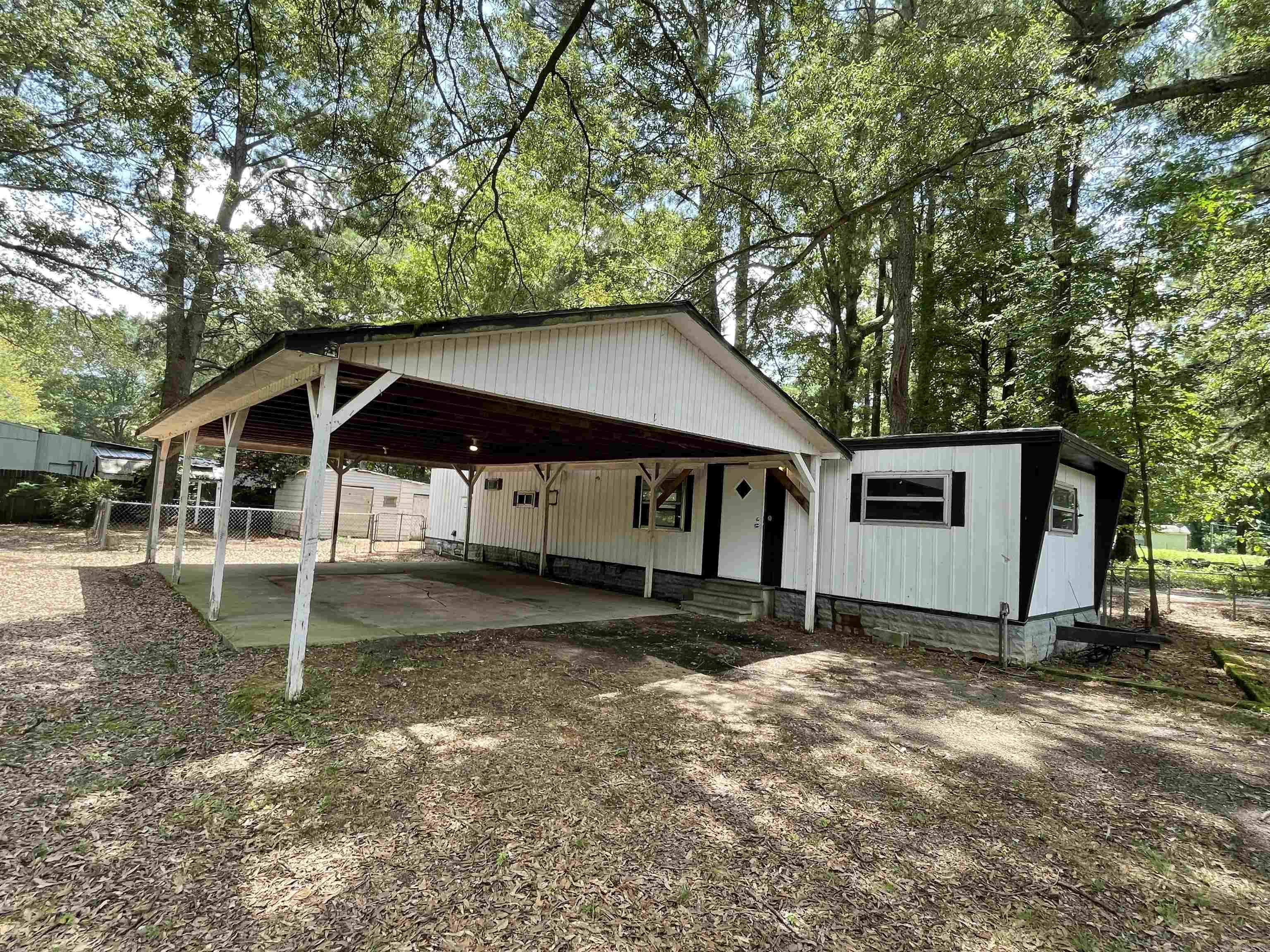 Large corner lot. Fenced yard. Lots of shade trees. Mobile home has been used as a rental since mid '90's. Good rental history with most recent monthly rent being $725 per month for the year 2025. In 2024, rent was $675 per month. Two car carport. Vinyl flooring throughout. Two window units used for ac & heat will convey as will the refrigerator. All electric. City water and sewer. Two storage buildings in back yard. Close to schools, shopping & medical facilities. Cash or in-house loan. Will not go secondary market. Sold AS IS. No seller disclosure as seller has not occupied property.