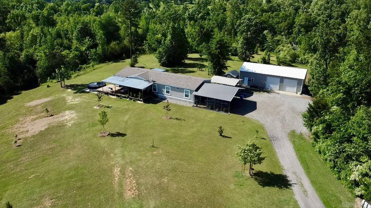 Escape to your private country retreat! Priced at its recent appraised value, this stunning 4BR, 3BA home with a den sits on 24.35 picturesque acres, offering rolling meadows, meandering branches, and breathtaking mountain vistas. The 2018 double-wide manufactured home features vaulted ceilings, custom cabinetry, a fully equipped kitchen with an oversized breakfast bar, and a brand-new induction range (2024). Enjoy the stocked pond, fruit trees, and grapevines, or relax on the front and rear decks overlooking the scenic landscape. A 30x50 metal shop with electric, plumbing, overhead doors, and a 12x12 heated/cooled space provides ample workspace. Additional perks include two carports, a storage building, an above-ground pool, and a safe and office desk that convey. Located just minutes from the Ozark National Forest, this property also boasts a main water line running through, allowing for potential additional home sites. Furniture, side-by-side, tools, and zero-turn mower negotiable. Don't miss this rare opportunity for privacy, convenience, and natural beauty!