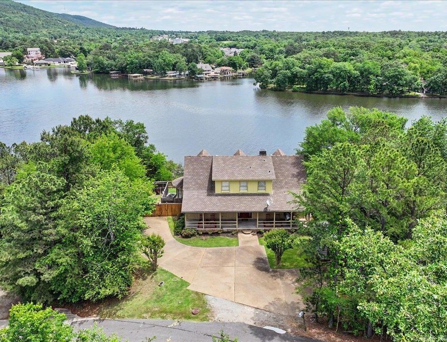 Experience breathtaking lakefront luxury log home living in this stunning 3-bed, 2 1/2-bath home spanning 2,172 sq ft in the sought-after Lake Ridge subdivision. Home off the beautiful Lake Hamilton spanning almost 8,000 surface acres invites you to enjoy fishing, recreational boating, swimming, skiing, jet skiing, and more. This luxurious haven features an airy, light filled floor plan. The great room has a wall of glass overlooking the lake with an awesome scenic mountainview in the distance. Upstairs is a balcony above the living room that provides another glamorous view of the sparkling lake. All 3 bedrooms provide a warm view of the lake with the 2 upstairs also having gabled ceilings. Long front porch, great for morning coffee as sun rises. Back deck great for grilling and gatherings (patio furniture and grill stays). The kitchen boasts stainless steal appliances to include a frig with lower french drawer freezer and gas stove for that chef inspired food prep taste. Two central air units add to the home’s efficiency. Cozy up to the woodburning (optional gas) fireplace during the chilly seasons. Don’t miss out on this luxury lake front home – schedule your private tour today!