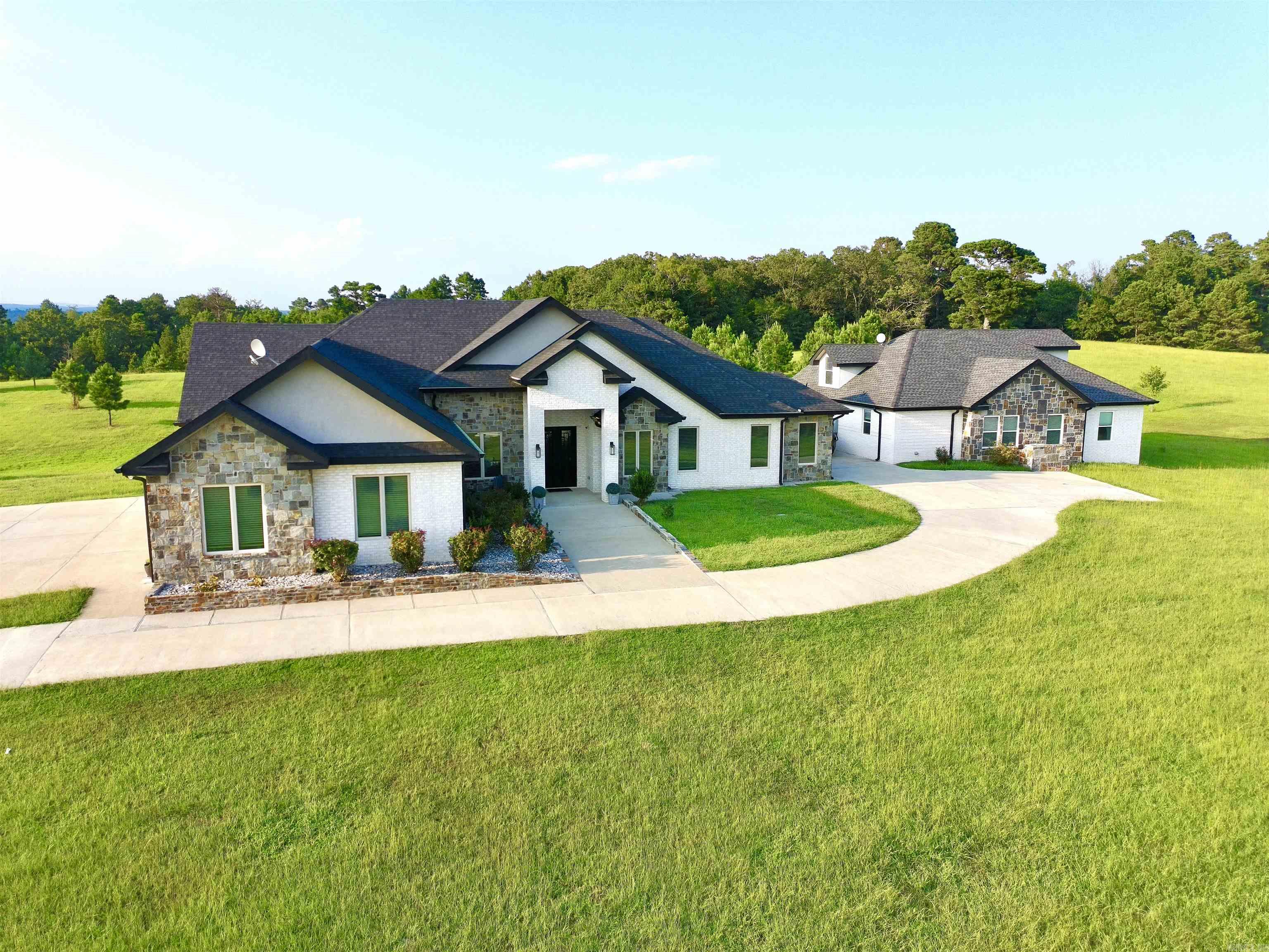 Dual-Home Private Estate on 6.8 Acres! Just 10 minutes from town, this rare property includes two full homes totaling 6 beds, 5.5 baths, and 5,311 sq ft. The main 3,349 sq ft residence features an open floor plan, 3-car garage, office, and 3 ensuite bedrooms. The primary suite includes a soaking tub, oversized walk-in shower, and a large closet that doubles as a reinforced storm shelter. The chefās kitchen has a double oven, high-end appliances, a large island with quartz waterfall countertops, and abundant counter space with custom cabinets. Expansive laundry room with extra storage, family room with 18-foot cathedral ceilings and rustic wood beams, and a private elegant office with 12-foot ceilings and built-in shelving. The 1,962 sq ft guest home offers private parking and entrance, 3 beds, 2 baths, laundry, and a spacious loft with stunning Ouachita Mountain viewsāperfect for an office, library, or playroom. Outdoor amenities include a shared 1,200 sq ft concrete patio, a 370 sq ft workshop/shed, a 10x10 chicken coop with 16 nesting boxes, and a fully fenced 10x20 chicken run. This private retreat is ideal for luxury, multigenerational living!
