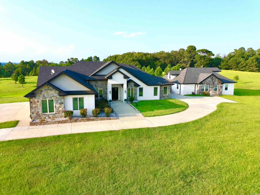 Dual-Home Private Estate on 6.8 Acres! Just 10 minutes from town, this rare property includes two full homes totaling 6 beds, 5.5 baths, and 5,311 sq ft.  The main 3,349 sq ft residence features an open floor plan, 3-car garage, office, and 3 ensuite bedrooms. The primary suite includes a soaking tub, oversized walk-in shower, and a large closet that doubles as a reinforced storm shelter. The chef’s kitchen has a double oven, high-end appliances, a large island with quartz waterfall countertops, and abundant counter space with custom cabinets. Expansive laundry room with extra storage, family room with 18-foot cathedral ceilings and rustic wood beams, and a private elegant office with 12-foot ceilings and built-in shelving.  The 1,962 sq ft guest home offers private parking and entrance, 3 beds, 2 baths, laundry, and a spacious loft with stunning Ouachita Mountain views—perfect for an office, library, or playroom.  Outdoor amenities include a shared 1,200 sq ft concrete patio, a 370 sq ft workshop/shed, a 10x10 chicken coop with 16 nesting boxes, and a fully fenced 10x20 chicken run.  This private retreat is ideal for luxury, multigenerational living!