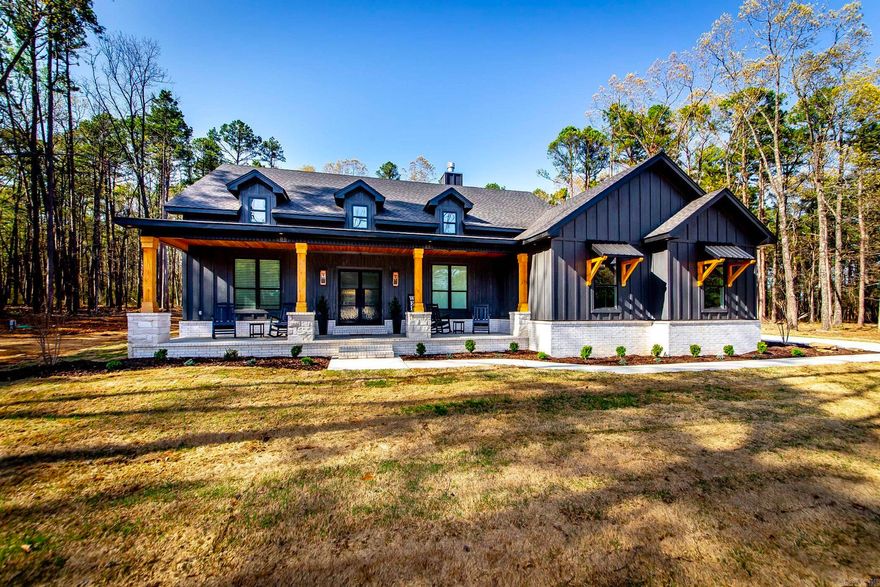 This charming 4-bedroom, 2-bath cabin sits just 1.5 miles from the marina—perfect for lake lovers and outdoor enthusiasts. The inviting entry features a rock accent wall and wooden beam ceiling detail, setting the tone for rustic elegance. Inside, the vaulted wood ceiling and rock fireplace in the living room create a warm, open space that flows into the kitchen with a large island and walk-in pantry. The primary suite boasts a vaulted ceiling, double vanities, and a custom tile shower. With 3 guest rooms and a bunk room, there's plenty of space for friends and family. Enjoy peaceful mornings and evenings on the covered front and back porches, gather under the pergola with a firepit, and keep all your lake gear in the shop with electricity. Bonus: this property offers prime hunting land with deer and turkey.