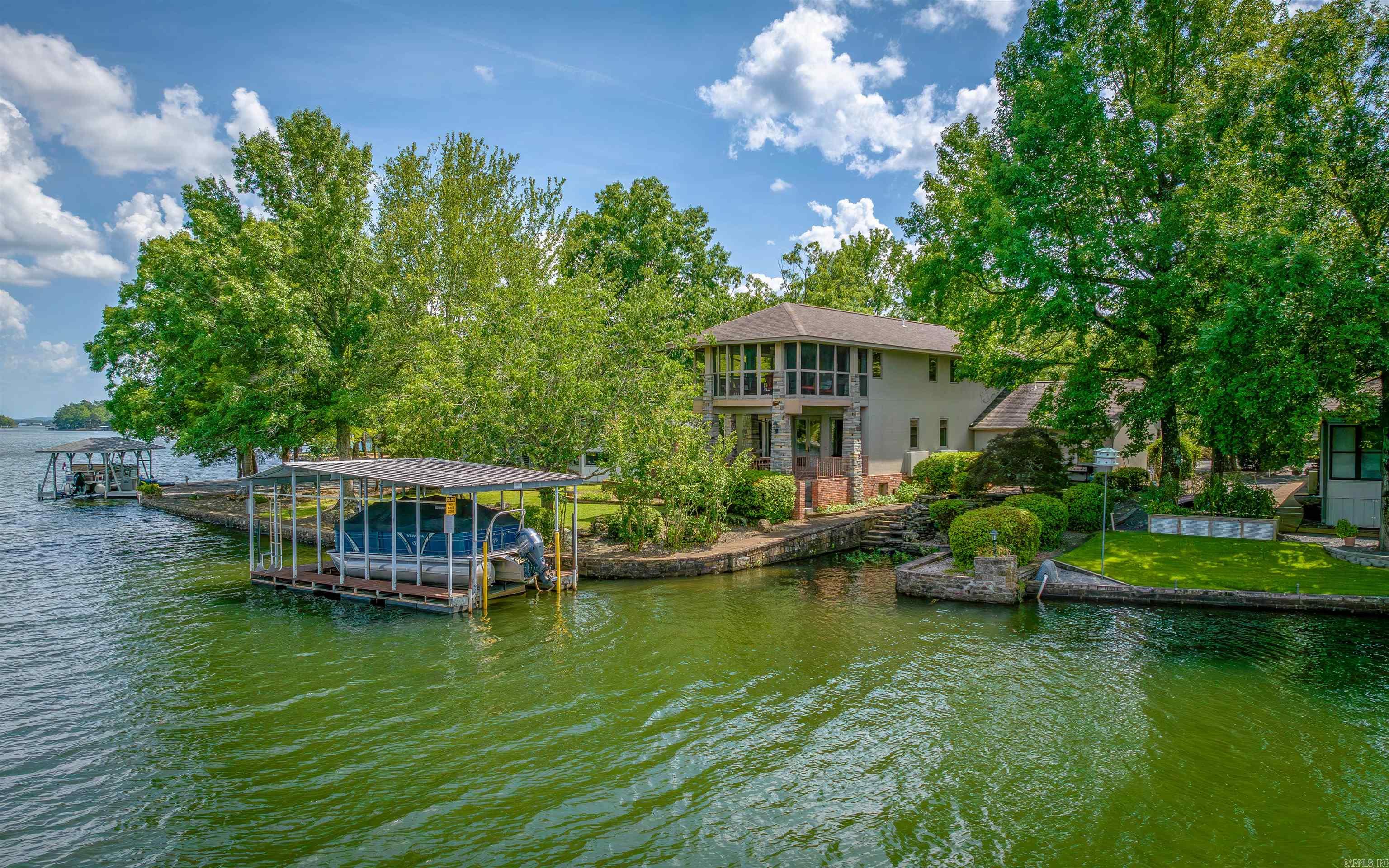 AMAZING architectural design on a Premium Lot on Lake Balboa! This Waterfront Oasis offers class from the Circular Drive with Water Fountain to the Elaborate Waterfall flowing into your own Boat Slip! Walls of windows all face the Lake including the Curved Living Room Wall! The Modern Kitchen with Corian Counters boasts TWO Islands! The Main Floor Primary Bedroom with High Ceiling overlooks the Lake and offers an Ensuite with Jetted Tub, Dual Vanities, and Walk-through Closet! The Two-story Stone Fireplace has a back staircase leading to the two Guest Rooms and Guest Bath upstairs, with a Wet/Coffee Bar Sitting Area opening to the Screened Porch overlooking the Lake! The Music Studio off the Oversized Garage, could be an additional Shop Area or additional Private Guest Room! Professional Landscaping with a mix of Brick and Quarried Stone will WOW you! Towering Pillars of Stone, and the 180+ degree water view is awe inspiring! This one-of-a-kind home is a must see! 10+ zone Irrigation System, Floating Boat Dock with Lift! Hot Springs Village is 26,000 Gated acres with 11 Lakes & 9 Golf Courses, Tennis, Pickleball, Performing Arts Center, Fitness Ctr, 20+Miles of Trails & much more!