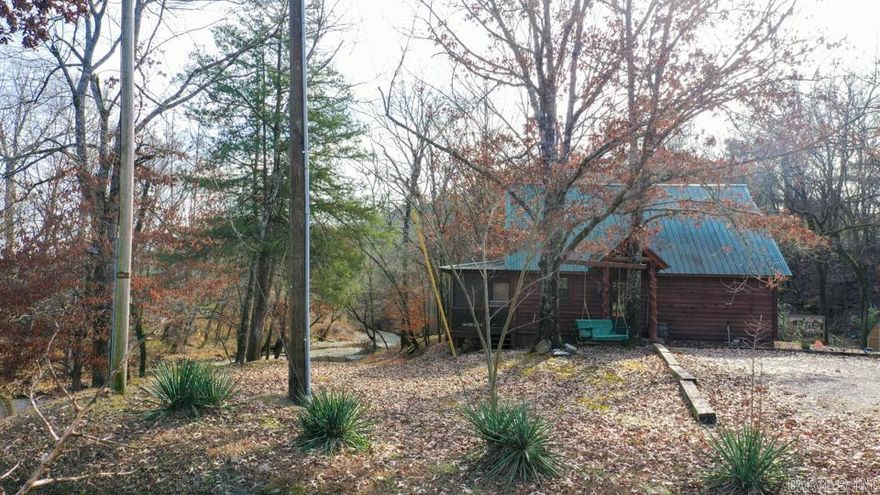 Charming log cabin nestled along the banks of Lick Creek in Norman, Arkansas. Currently operating as a successful vacation rental, with profit and loss statements available upon an accepted offer. In addition to the cabin, the property includes extra creekside land featuring RV hookups—perfect for expanding rental income or hosting guests. The cabin offers a warm and inviting layout with two bedrooms on the main level and a spacious loft upstairs. It is being sold fully furnished, making it truly turnkey. Enjoy peaceful creek views from the screened-in porch, which opens to a back deck with a seating area and hot tub. Beyond the deck, a fire pit and outdoor seating create the ideal setting for relaxing evenings by the water. Recent owner improvements include a new HVAC system, tankless water heater, refrigerator, fireplace insert, hot tub cover and heater, washer and dryer, and new water lines to exterior spigots. This unique creekside retreat combines rustic charm with modern upgrades and income-producing potential.