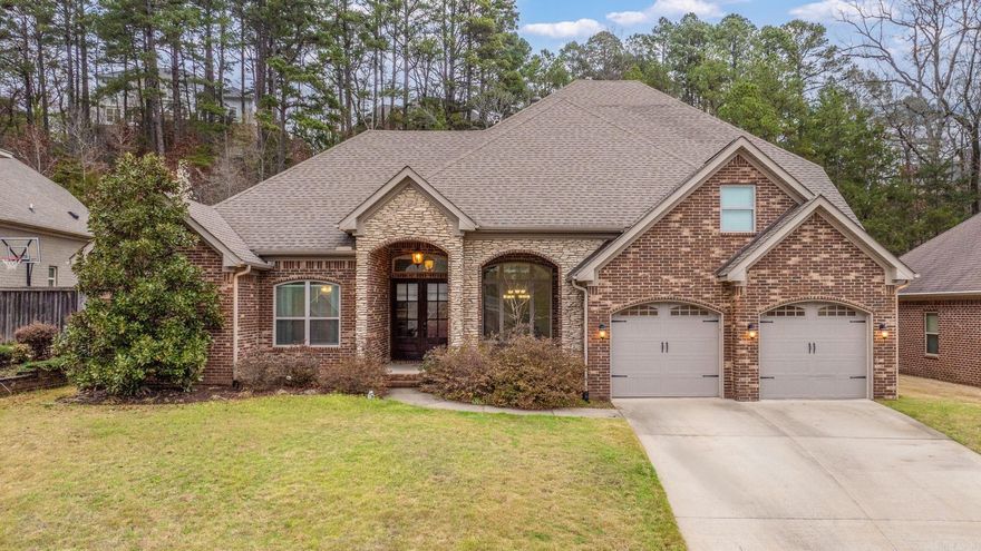 Some homes stop you before you've even stepped inside. This is one of them. The rich brick and stone façade, towering tree backdrop, and classic curb appeal set the stage for what awaits within. Soaring trey ceilings, decorative columns, and gleaming hardwood floors flow throughout a plan built for living and entertaining. The kitchen is the undeniable heart — custom dark-stained cabinetry, carved corbel details, dual granite islands, stone tile backsplash, gas cooktop, and stainless appliances. A sun-drenched casual dining space opens seamlessly from the kitchen, while the formal dining room impresses with its coffered ceiling, statement chandelier, and elegant proportions worthy of any occasion. Upstairs, generous bedrooms with crown molding, a private guest en-suite, a bonus room with coffered ceiling, and a flex workspace offer room to grow. Outside, Woodlands Edge delivers — resort-style pool, nearby park, and a community that matches this home's caliber. 13414 Foxfield Lane isn't just a place to live. It's a home that grows with you.