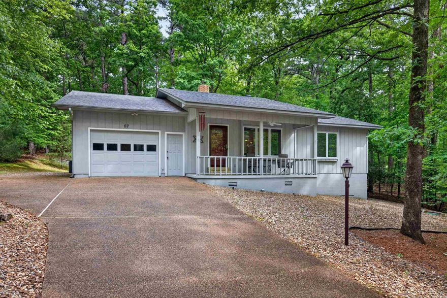 Inviting front porch welcomes you to this immaculate home surrounded by trees for ultimate privacy.  Living room features large picture window, bult in shelves and wood burning stove.  Kitchen cabinets are a very nice upgrade with pull outs and lots of storage plus an island.  Kitchen connects to laundry with matching cabinetry for additional storage, sink and desk area.  Dining room overlooks wooded back yard and spacious deck.  Two bedrooms complete the interior of this charming home.  Primary has private bath with walk in shower and full wall closet.  Second bedroom has access to second bath. Both bedrooms are exceptionally large.  Garage includes door opener, workshop area and opens to deck.  Very well loved home. Hot Springs Village boasts 9 golf courses, 11 lakes, pickleball, hiking trails, white sand beach, tennis, fitness center, indoor and outdoor pools and so  much more.  Half an hour from Hot Springs or Benton and one hour from Little Rock airport.. HSV has one time $2000 buy in for new residents.