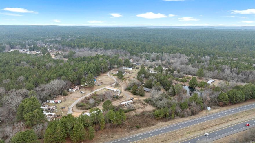 There is a 3 Bedroom, 1 bath brick home on the property. The owner said that it is of No Value & Is not livable. It does convey with the acreage. There is a pond, very grown up around it. The Mobile Home park was set up with over 30 spaces. None of the Mobile homes will remain with the property. Easy access from I-30 for any type of business.  Per Clark County there is 15.24 acres. The owner says it is only 14.74 acres per the deeds. Per owner, property is zoned R-1, single home residential. It is currently used as a Mobile Home Park and has been for many years. Any changes to zoning will need to be addressed with the city.