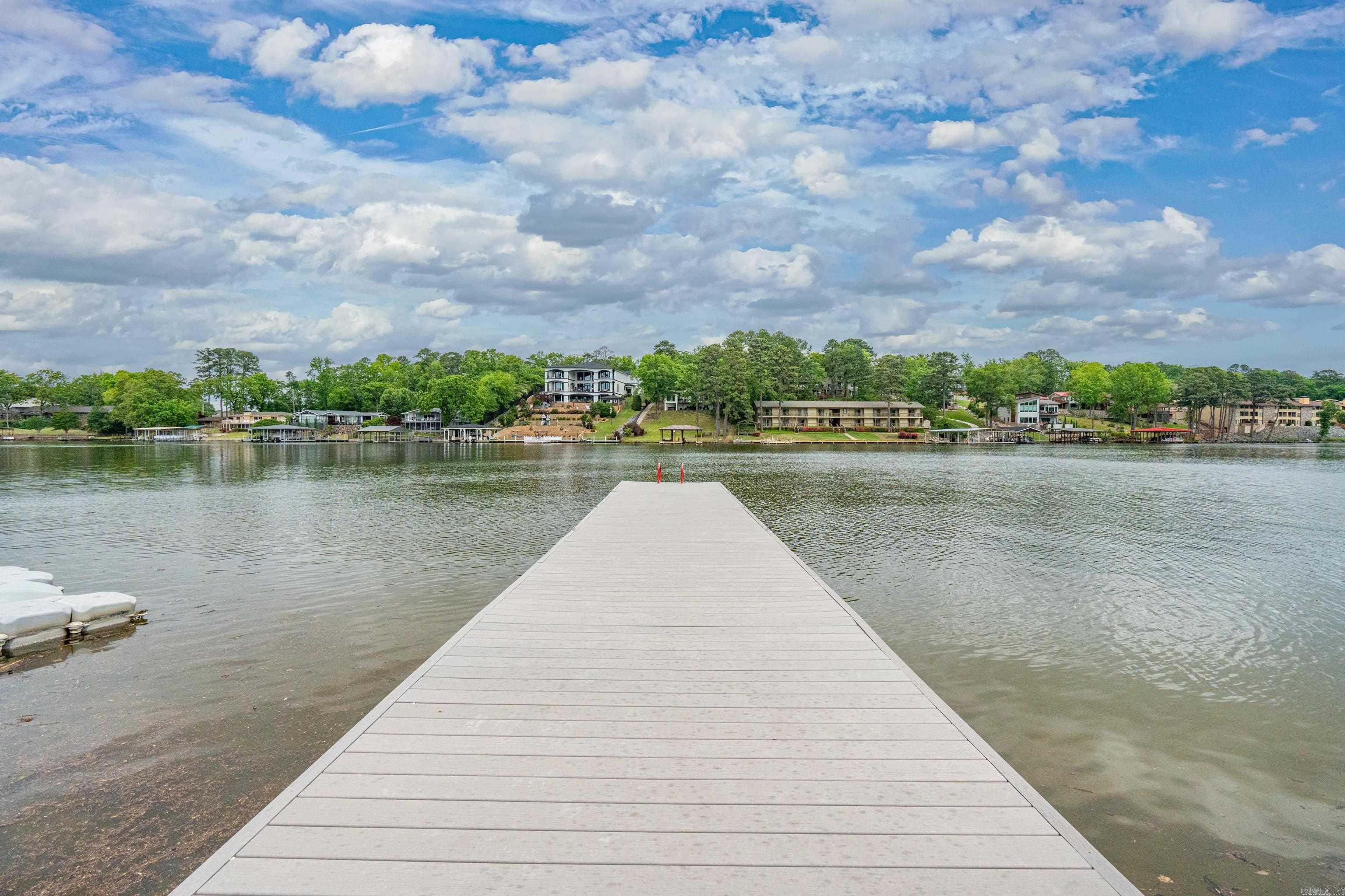 Tired of sunsets not featuring in your Instagram grid? Letās fix that. Welcome to your own slice of lakeside paradise on Lake Hamiltonāwhere the sunsets are free, but the views are priceless (okay, technically itās included in the HOA). This updated 2-bedroom, 2-bath, 1520-square-foot beauty is basically a resort disguised as a condo. Itās light, bright, and ready to help you live your best #LakeLife. Weāre talking fireplace for your winter hot cocoa vibes, a whirlpool tub for bubble bath royalty status, and stainless appliances that almost make doing dishes fun. The lanai (fancy word for "sweet covered patio") runs the entire width of the unit, so youāve got front row seats to poolside drama or peaceful loungingāyour call. Access it from both the living area and the primary suite, because you deserve options. Hate stairs? Us too. Thatās why thereās an elevator. And yes, this place is in a gated community with covered parking because your car deserves a little pampering too. Bottom line: if youāre looking for a dreamy lakefront condo with serious vacation energy (but without the checkout time), this is it. Just donāt blame us when your guests refuse to leave.