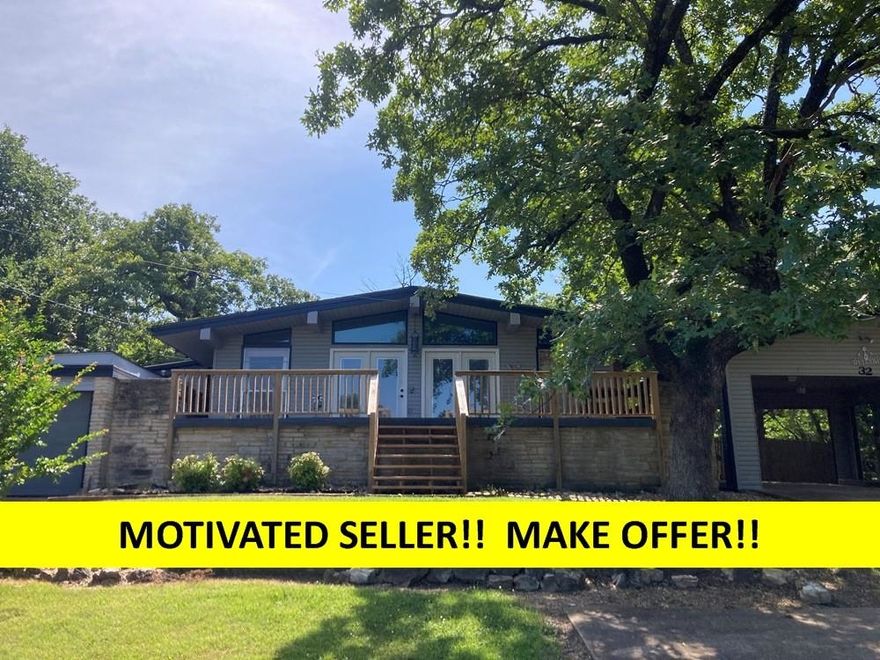 MOTIVATED SELLER LOOKING FOR AN OFFER!   HOME on 2 LOTS OVERLOOKING THE OZARK FOOTHILLS!  3-bedroom + Den,  2 1/2 bathrooms, with a double carport & a 1-car garage/shop all sitting on a hill with a large front deck. This could be YOUR HOME or RENTAL INVESTMENT! A new roof & gutters installed as well as a new deck on the front of the house in 2024. Lots of updates in the past 5 years. Living rm with vaulted beamed ceilings & electric fireplace and a gas back-up ventless wall heater to knock-out those cool mornings with lots of natural light makes the home bright & airy. Step out onto the new front deck to enjoy your morning coffee or evening drinks. Cute kitchen with a large butcher block counter top has been recently updated with all New Stainless-Steel Appliances and a neat farm sink. Large & convenient laundry comes with a stackable washer & dryer along with a folding table & soaking sink. Separate den or could be a 4th bedroom.   Just down the hall is a separate bedroom with its own split H&A unit and 3/4 bath. The back yard is completely fenced to keep your pets safe & secure.  Listing #2396.  (Sqft, measurements, taxes are per ARCoData)