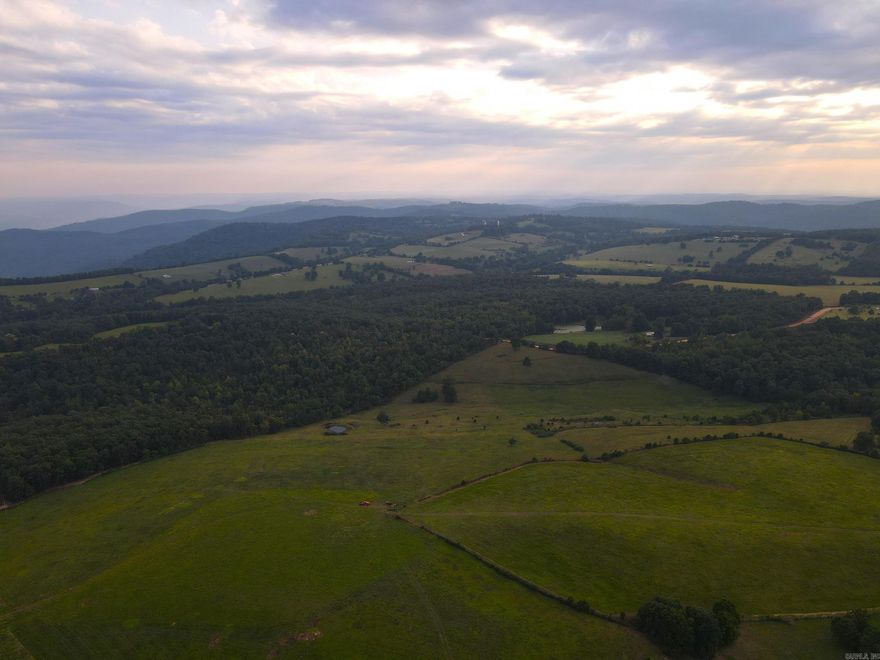 What a spectacularly rare find in a highly desirable region just minutes to Ponca, AR, and the headwaters of the famous Buffalo National River. Stunning scenery is literally at every turn as you navigate this gently rolling majestic tract. The county gravel road Along the south boundary provides quality access at multiple spots. Leaving all the options open for any use is possible by the complement of electric, county rural water, telephone, and internet. As you round the bend of the road and set your eyes on this special tract, you can almost feel the generations of work, blood, sweat, tears, heart, and soul poured into the land. This dirt is truly different than any you will see and provides some of the most unique opportunities that land in this area will give. The property is fully fenced and has run cattle effectively and efficiently for decades, with high-quality pasture and even multiple ponds to boot. One of the things you just can’t duplicate is the natural God-given topography of the ground, and this tract is the ideal mix of level and rolling land. An old homestead once set atop one of the flats and is complete with a hand dug rock lined well that is still holding water.