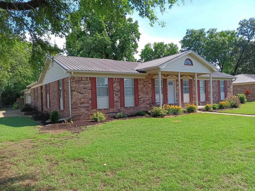 Spacious 4 bedroom, 3 bath brick house with metal roof, covered patio, long covered porch on front, storage building, storm shelter & fenced in back yard. Tile floors in the kitchen, dining, office & baths with hardwood floors in the rest. Two living areas that can be used as a bonus or game room & one has a wood fireplace with insert. Trane HVAC (10-year warranty) was replaced 4 years ago & the water heater has been updated. This house also has a couple of large shade trees, gutters & a 2 car garage with extra parking pad connected. See agent remarks.