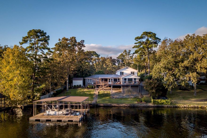 Exceptional luxury lakefront home on Lake Hamilton with 110’ of shoreline and a nightly rental permit that conveys—offering immediateinvestment opportunity or the perfect private retreat. Ideally located on the north side of the lake, this property combines peacefulwaterfront living with convenient access to Oaklawn, shopping, dining, and all that Hot Springs has to offer—just minutes away.Spanning approximately 3,770 square feet, the home features a bright open floor plan designed to capture stunning lake views from themain living areas. Large windows and seamless indoor-outdoor flow lead to an expansive lakeside deck—perfect for entertaining,relaxing, and enjoying unforgettable sunsets. The property includes a private boat dock with swimming platform, and offers the rareadvantage of main channel views while being set slightly back in a wide cove—providing both panoramic scenery and calmer watersideal for swimming, floating, and lake activities. Designed to accommodate large gatherings with ease, the home offers multiple livingand entertaining spaces. The upper level includes a spacious bonus room with bunk area and flexible space for recreation, along withtwo king bedrooms and a