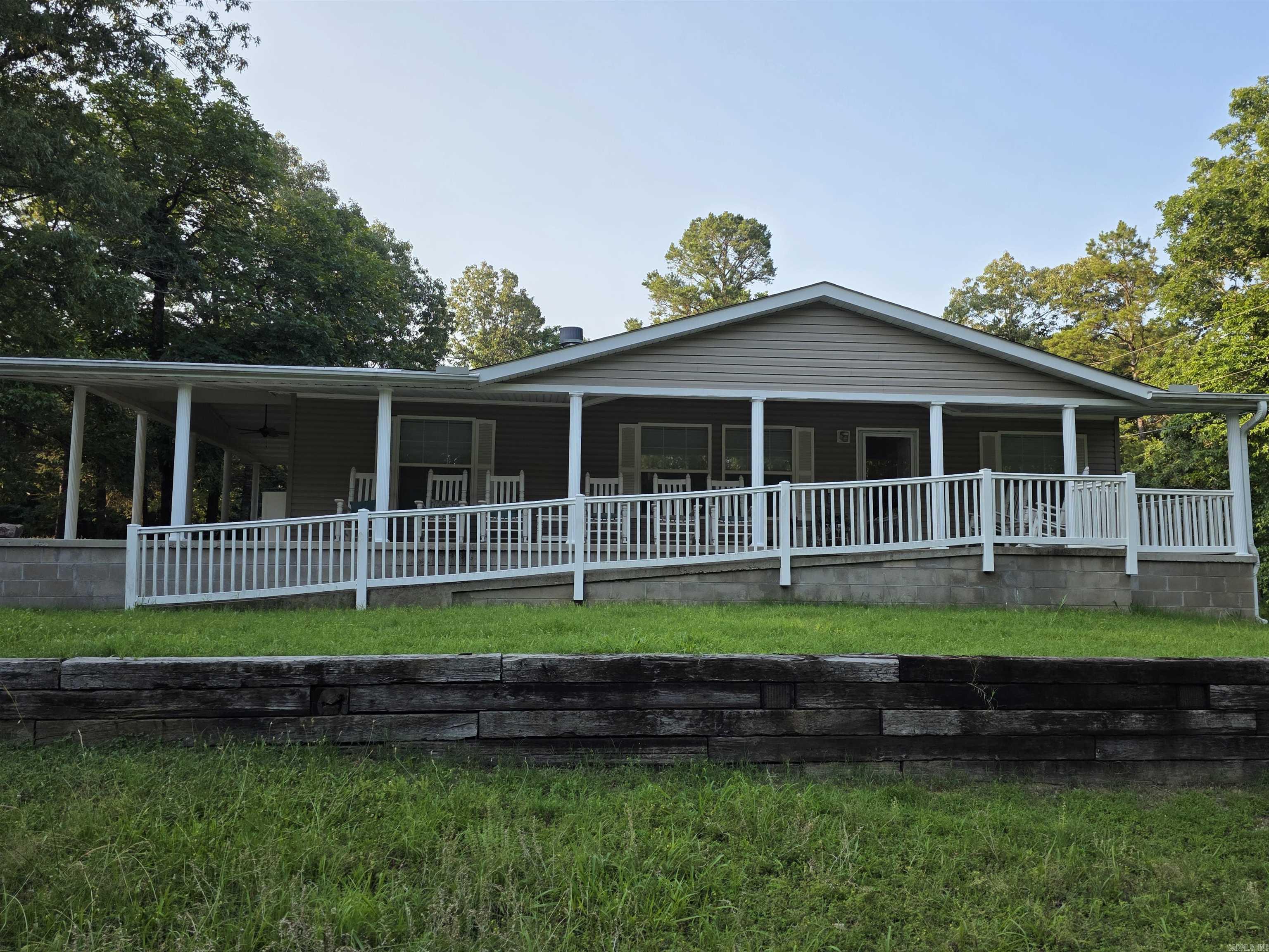 This charming Southwest-style home features 3 bedrooms and 2 bathrooms, offering 1,350 square feet of comfortable living space, all set on 5 acres (M/L) of beautifully laid-out land. The property boasts expansive front and side porches, providing the perfect spaces for relaxation or entertaining while enjoying the serene surroundings. Inside, the cozy family room includes a welcoming fireplace, ideal for chilly evenings. The spacious kitchen, complete with a large island, offers ample counter space and storage for all your culinary needs. The land itself is level and easy to maintain, with plenty of room for additional homes or future expansion. Located just a short drive from Lake Norfork and the White and Norfork Rivers, this home offers the ideal combination of privacy and proximity to outdoor recreation. Priced at $231,500, this property is an excellent opportunity to embrace country living while staying close to local lakes and rivers.