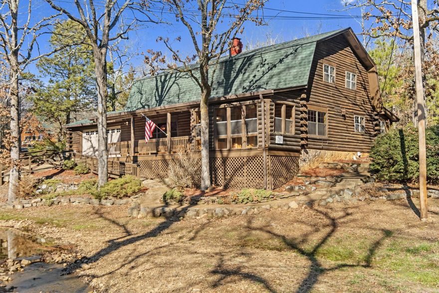 Check out this stunning log cabin situated on over 1 acre that offers a peaceful and private retreat.  The log cabin features a spacious and rustic design with 5 bedrooms and 3 full baths, providing ample space for family and guest. Two Primary bedrooms one up and one down. The living area is perfect for gathering and relaxing, while the kitchen is equipped with a Jenair stove and built-in wine cooler. Downstairs laundry room is huge with lots of space for storage, while upstairs you will find another laundry.   Watch the deer and enjoy the creek from the privacy of your enclosed front porch.  Roof was replaced in 2023. Exterior was sealed in April 2021, jet system septic and much more.