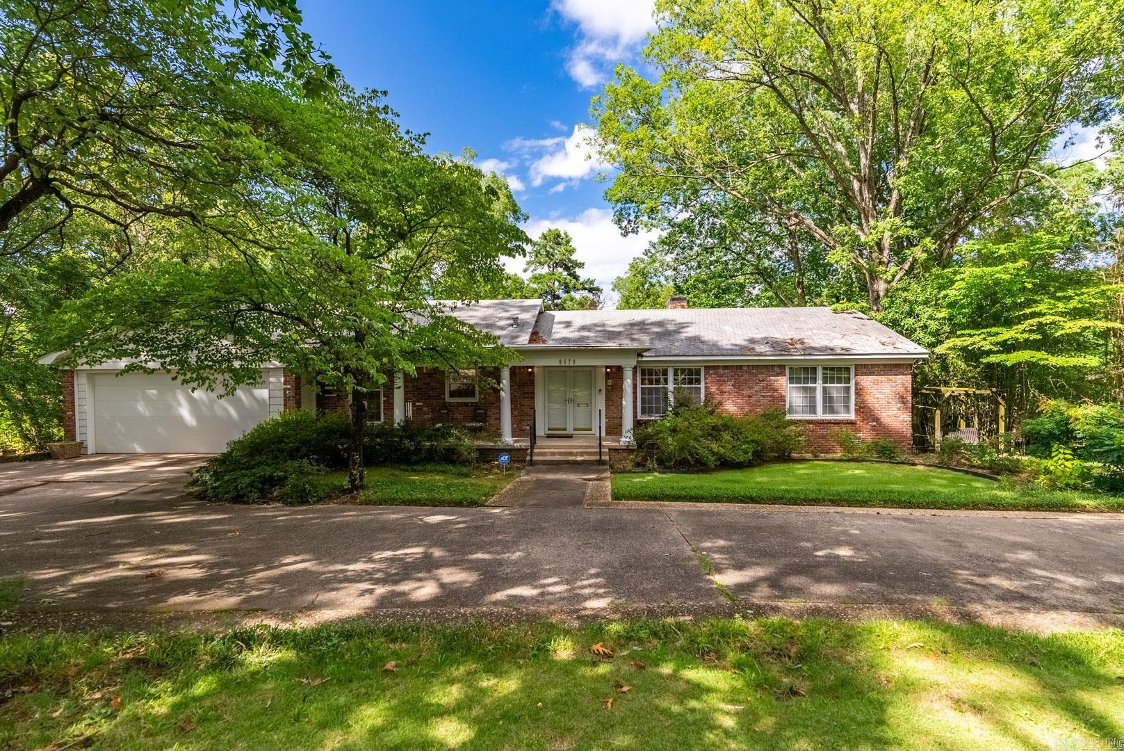 Lovely mid-century architectural home located on an acre of wooded land in the heart of the city. Great floor plan for family living and entertaining with plenty of room for everyone! Beautiful hardwood floors and large windows with picturesque views of the surrounding trees. Formal living room, spacious kitchen and dedicated dining area. Open family room flanked by original gas log brick fireplace with direct access to fabulous deck with stunning vista views overlooking the large, tranquil private backyard. Separate primary bedroom on the main level with ensuite bath. Two additional guest bedrooms and bath on the main level. The downstairs layout is ideal with a paneled, second living area featuring a stone gas log fireplace with sliding glass doors leading out to a covered patio and fenced backyard. Fourth bedroom and bath also located on this lower level. Additional space perfect for an art studio or private office. Laundry room located on lower level connected to the abundant storage area. Two car garage and wide circle driveway with additional side parking pads. Come see!