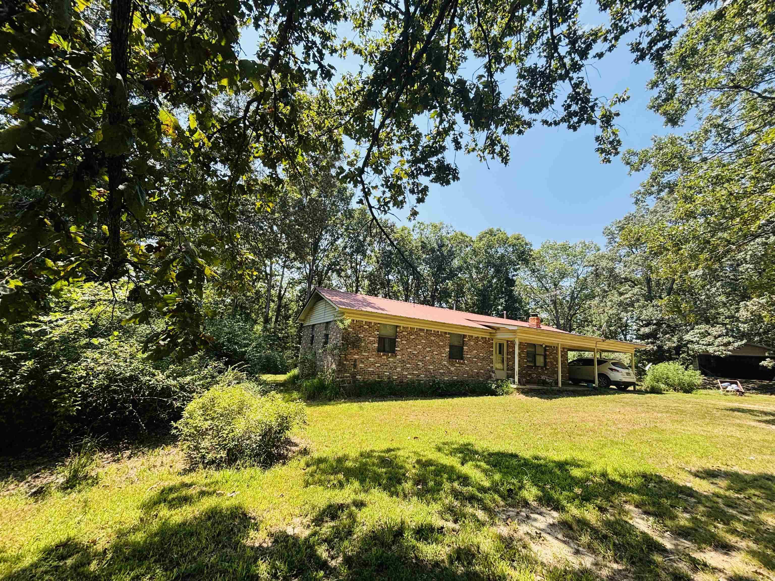This 3 bedroom, 2 bath country home located in a beautiful area near world renown Mountain View and the Ozark National Forest is situated on almost 7 mostly wooded acres MOL providing ample space for landscaping, gardening, raising animals, and creating private outdoor living space. The classic brick exterior with a newer metal roof has curb appeal but is potentially in need of some minor repairs or a refresh. The spacious interior is currently occupied and fully functional but with some repairs, updates, and renovation could be revitalized into a beautiful modern home. It has a large family room/den addition that can also be utilized as a fourth bedroom or home office. The small but practical galley kitchen has a built-in stove top and wall oven and leads to a laundry room with washer/dryer and pantry storage. The primary bedroom has an ensuite bath with walk-in shower. The main bath has a tub/shower combination for those who prefer a tub. Central heat and air plus a wood burning stove in the living room, private septic, propane tank, garden area plus a detached garage/shop. This property is a great option for those wanting a rural home with acreage.