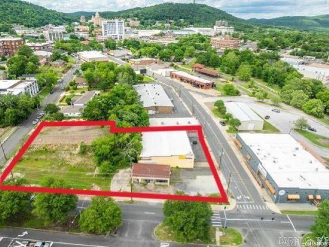 This rare full block-front commercial property offers a high-exposure development opportunity in one of Hot Springs' fastest-growing business corridors. Located at 454 Broadway Street and 208 & 214 West Grand Avenue, the site spans just over one acre and includes more than 8,000 square feet of existing building space. With approximately 620 feet of total road frontage—307 feet of which is directly on West Grand Avenue, a high-traffic thoroughfare with over 20,000 vehicles passing daily—this property provides unmatched visibility and access for future development. Zoned CBD (Central Business District) and located within a designated Federal Opportunity Zone, the site allows for a wide range of commercial uses while offering valuable tax incentives for qualified investors. Over the past three years, the surrounding area has experienced significant commercial expansion, including the addition of national hotel chains, restaurants, retail shops, and service providers, making this one of the most active and high-demand corridors in the Hot Springs market. The property’s prominent location and full block-front exposure make it ideal for a flagship hotel, entertainment venue, shopping c