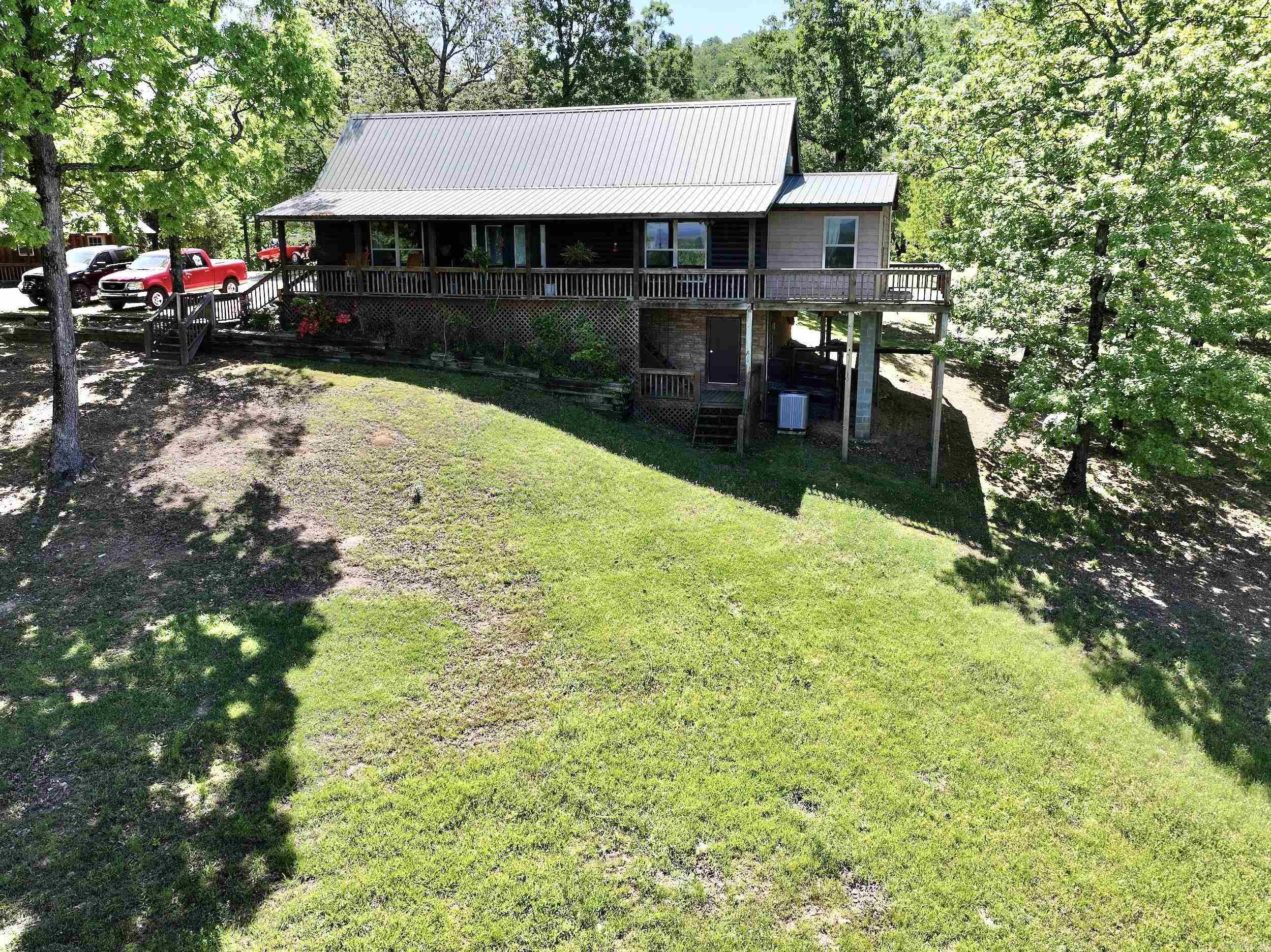 MOTIVATED SELLER! House and cabins! Perched atop a mountain & adjoining Corp Land, this enchanting cabin showcases awe-inspiring panoramas. The main cabin hosts 2 bedrooms and 1.5 baths, & has been recently renovated to perfection, adorned with exquisite details at every turn. Spanning over 11.39± acres of land, it offers complete seclusion & serenity. There's also a separate cabin perfect for guests, to be used as a bunk house, or as a mother-in-law suite, complete with additional bedrooms, its own kitchen, & bathroom. Several cozy cabins are nestled on the property, as well as a 30X30 shop with showers & bathrooms, presenting opportunities for renovation to create potential income streams. For RV enthusiasts, there are 5 hookups available with 30/50 amp. The property's versatility offers potential for both generating income and investing. Embrace outdoor living at its finest with amenities such as a greenhouse, safe room, covered entertaining area, a charming fire pit, & includes a new water filtration system for the well. Access nearby Lake Greeson or venture onto the local Bear Creek ATV trails right from your doorstep. Agents see remarks