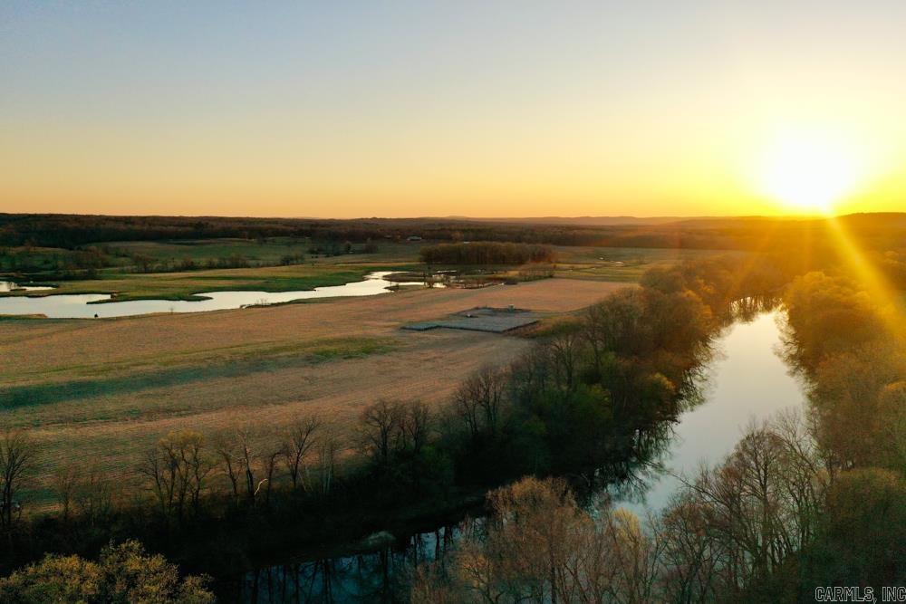 Discover a rare opportunity to own a stunning 513 +/- acre legacy property in Pangburn, Arkansas, just 20 minutes from Searcy. Boasting 1.6 miles of pristine Little Red River frontage, this exceptional property offers unmatched beauty and functionality. Perched atop a scenic hillside, a custom-built 2,675-square-foot home overlooks lush pastures, tranquil ponds, and the meandering river below. The estate features 6 ponds totaling approximately 20 acres of water, providing both aesthetic charm and functional sources. For aviation convenience, a 900-yard private airstrip can be refreshed for use, this feature just ads to the unique infrastructure that could be used for additional accessibility. Encompassing vast, pristine pasture grounds, the property showcases lush, well-maintained fields ideal for grazing, recreation, or potential development. Approximately 120 acres of fertile riverfront pasture produces rich Bermuda grass that has irrigation infrastructure including a center pivot system, ideal for hay production or grazing. The rest of the property is fenced and cross-fenced, ensuring efficient livestock management.