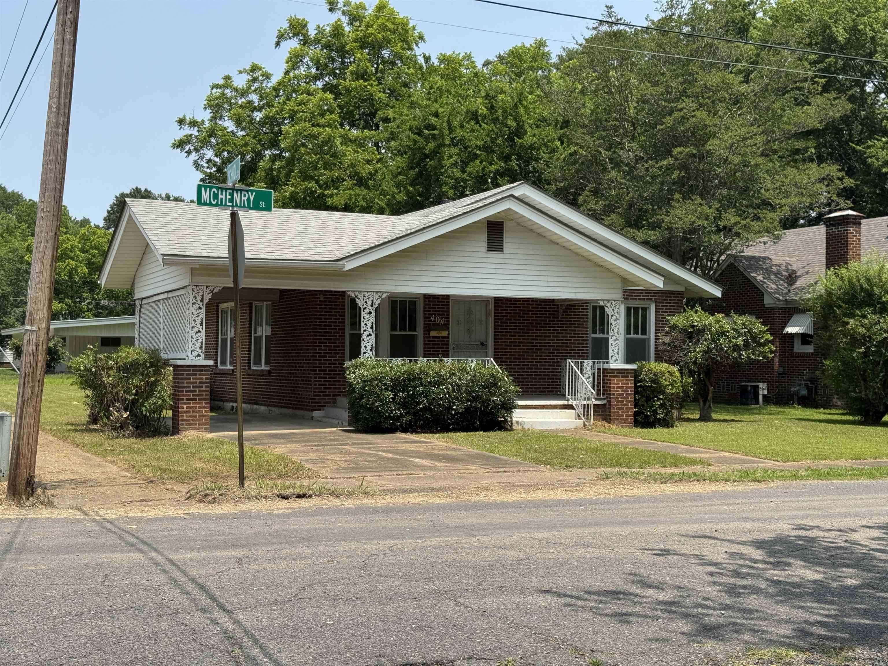Charm from time gone by, 3-bedroom, 1.5 bath brick home on a corner lot. Original hardwood floors add warmth and character throughout. The retro kitchen offers vintage charm and leads into a cozy dining area featuring a unique mid-century light fixture. The living area is bright and inviting with large windows and great lighting. All bedrooms are good size with good size closets. Middle room offers a fireplace, could be used for bedroom or for den/study. The home includes a one-car carport, additional driveway parking and a convenient laundry area. Outside, enjoy a manageable yard with mature trees and established landscaping. Solid construction, timeless appeal and loads of potential-perfect for first-time buyers, downsizers, or anyone who appreciates classic style. Located close to schools and downtown shopping. 30 minutes from Hot Spring National Park.