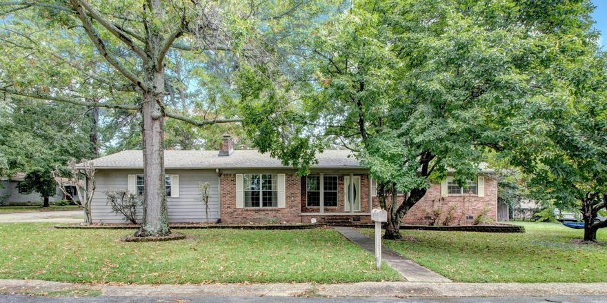 Nestled on a landscaped corner lot surrounded by mature trees, this charming home offers timeless character and modern comforts. Inside, you'll find original hardwood floors, custom built-ins, and two cozy wood-burning fireplaces that add warmth and style. The spacious great room and sunroom are flooded with natural light, thanks to stunning floor-to-ceiling windows that bring the outdoors in. The primary bath features a jetted, soaking tub and a separate shower. Perfect for both everyday living and entertaining, the property also features a private backyard with a covered patio deck, a gazebo, a handy storage shed. New roof in 2025. Agents, see remarks.