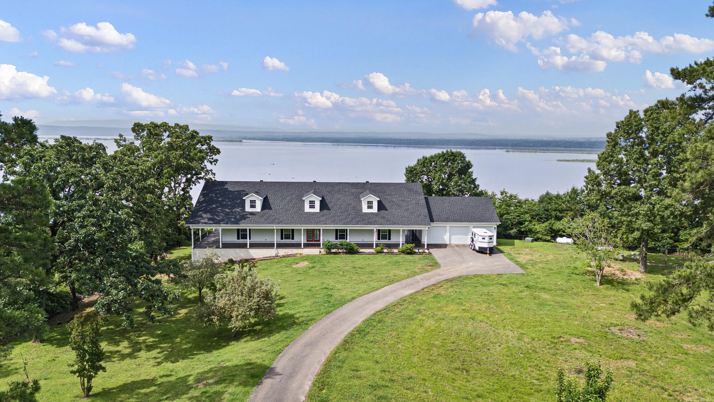 Miraculous, panoramic views and a grand home on the water! On the interior, you will find 3500 SF, open floorplan, 3 BRs, 2.5 baths, a large office/study with built-ins surrounding so it could be used as a library, laundry room and ample storage closets and storage rooms throughout the home. There is also an additional room off of the breezeway that is heated & cooled and could easily be turned into an additional bedroom by adding a closet space. On the exterior you will find a covered porch that wraps around the entire home and 3 car garage with a heated & cooled work room. The large storage space with overhead door access under the home has a cellar with electric. If finished this could add 1,000 SF. New HVAC (2). New roof. All top of the line appliances. Propane tank for new Viking gas range. New fencing surrounding property.