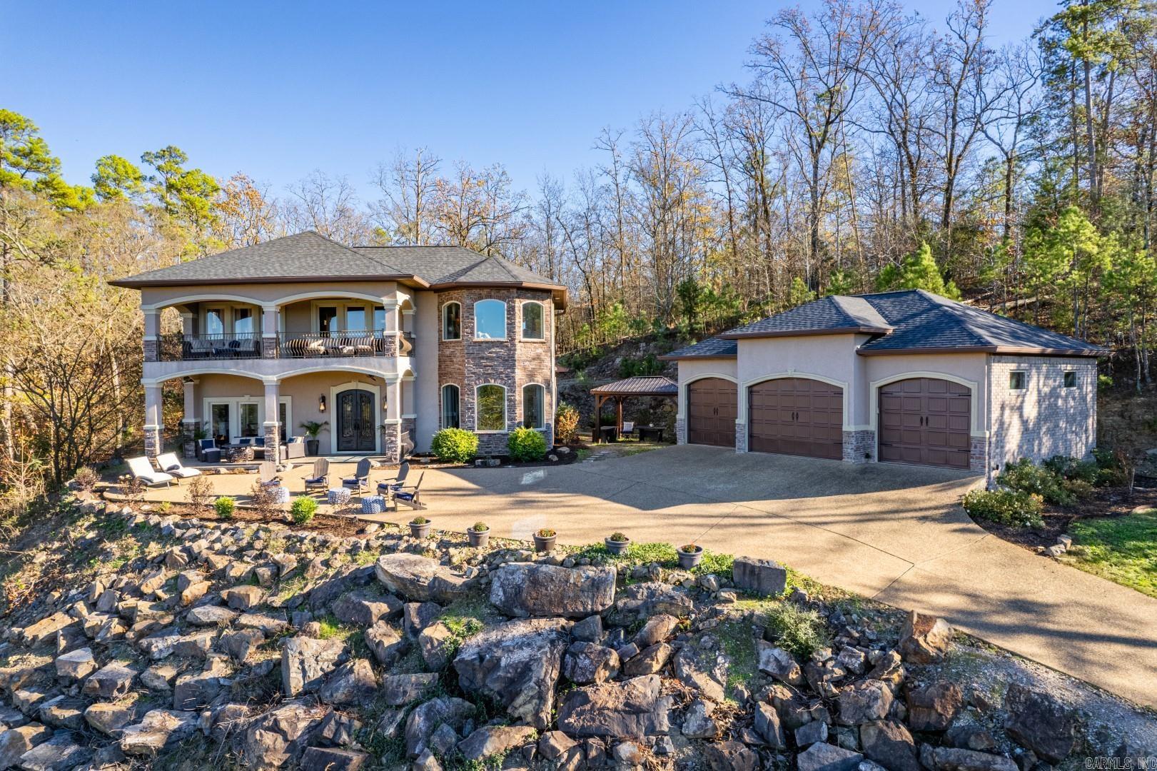 Enjoy breathtaking sunsets over Lake Hamilton from this majestic home with unobstructed views of stars and mountains, including Mount Magazine. Located minutes from town, yet nestled in a serene, gated community of upscale homes with lake access for fishing and water activities. This luxurious 3-bedroom, 3 ½ bath home offers privacy, lake views, and nature teaming with deer. The main level hosts an office and the primary bedroom with outdoor entry. An upstairs balcony is accessible from the family room and a bedroom. Features include custom cabinetry, granite countertops, tray ceilings, professional fridge/freezer combo, ice maker, large walk-in pantry, 3 walk-in closets, 2 walk-in showers, bamboo hardwood floors, tiled bathrooms, central vacuums, alarm system, detached 3-bay garage with EV station hookup, and exposed aggregate concrete driveway and front seating area. Built in 2015, this home offers a first-floor living area of 1,749.34 sq ft, a second floor of 1,250.2 sq ft, and a 947.21 sq ft garage. All major appliances are included.