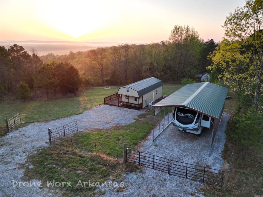 Fully furnished cabin for sale!   This one, "The Launch Pad", is the perfect property for the Traveler or Minimalist. Mostly wooded 20 acres, +/- , there is minor maintenance for this lot where you can come and go easily.  Park your own RV or 5th wheel for the times you stay at this micro studio cabin then hook up and head off to see the country.    This parcel has its own water meter and electricity, a tiny loft with two more beds.  Whether you want to make this "turn key" cabin into a short term rental or make it your launch pad, it's your choice.  For the hunter, this could be your whitetail, bear, or turkey getaway.    Imagine yourself taking in a hot cup a joe as the sun rises off the deck overlooking the gorgeous view or relax the evening away with a glass of wine with dinner under the Ozark Mountain sunset.  If you're looking for a simpler, quieter life without all the stress, this just might be your final destination.    The actual tax amount will be adjusted off the total parcel if you decide to purchase this smaller lot from the larger tract.