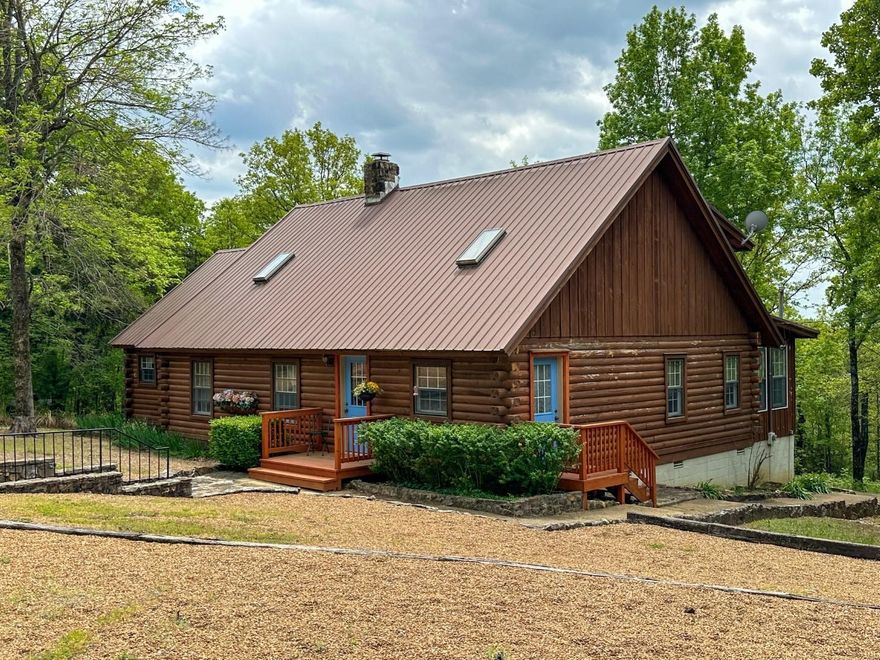 Country Log Home…30 Wooded Acres +- of privacy with a huge old log design that centers around a massive 10’ native stone fireplace also serving as a natural divide between living, kitchen, dining, family and primary bedroom area. In addition to the open center stairway to the loft bedrooms & bath, a stairway to a 2nd loft leads to your special treasures in the primary (main level) bedroom with bath. Outside the woods are largely oak trees, with the detached carport embracing use of the stone walkway, while the native stone also accentuates huge log beams within.  An enclosed porch and open deck to the serenity of the Ozarks captures your favorite views, while a gentle rain on the metal roof is exactly what many are seeking as they peacefully read their favorite novel.
