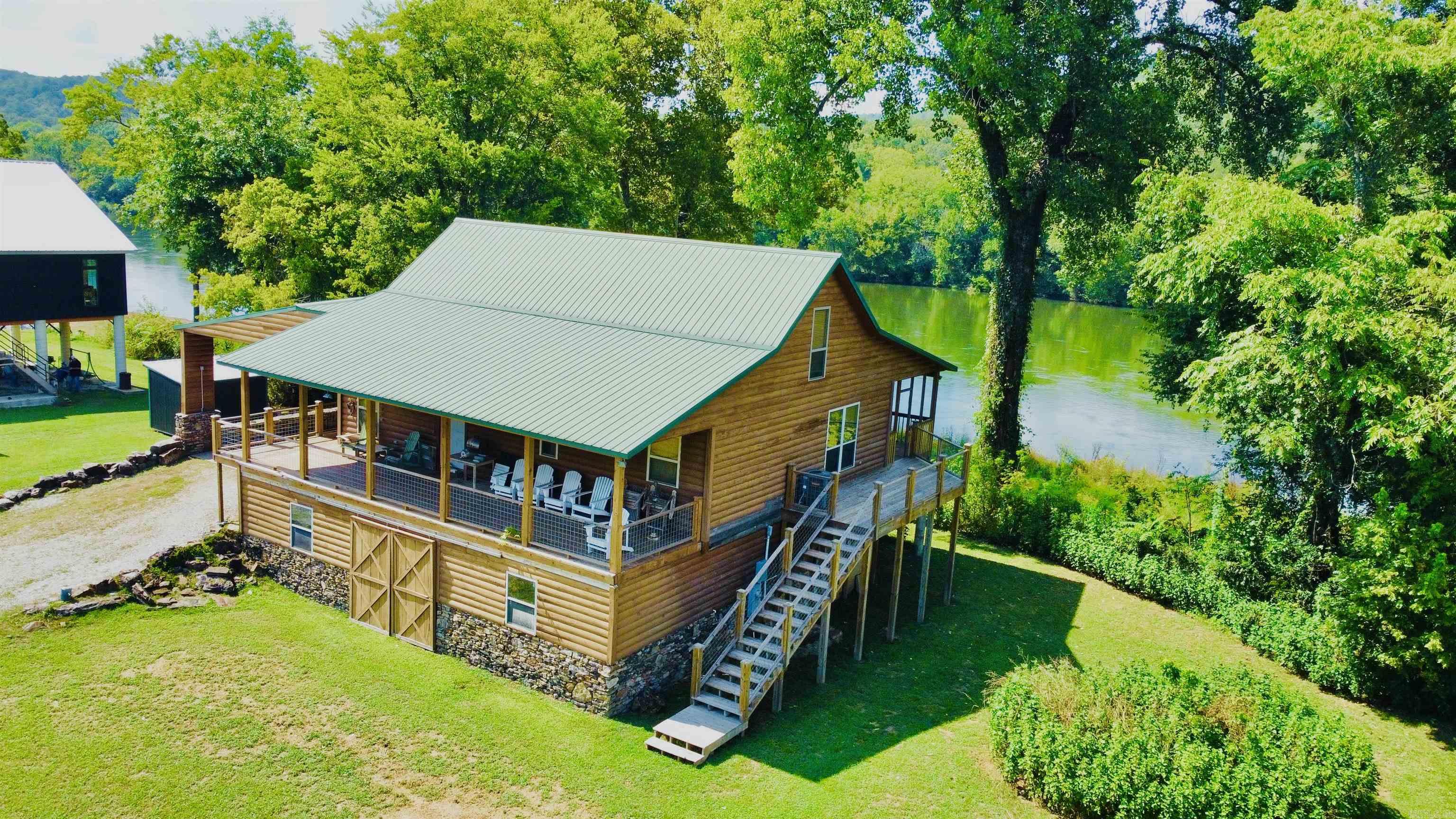 Located in the coveted Ozarks this dream property not only fronts beautiful White River but is just minutes from the music, eateries, & festivals of world renown Mountain View! Quiet & peaceful River Valley offers unmatched sunrise & sunset views, excellent trout fishing, plus a boat launch. Enjoy watching eagles, deer, otters, & geese from back porch or while BBQing in the outdoor kitchen followed by star gazing around the large outdoor stone fireplace. The well-designed cabin is raised with a river rock filled concrete block foundation, slab floor, & ceiling offering a large unfinished area plus a 10ā12-person safe room. The main floor has a timeless rustic cabin feel, open concept design, warm rich wood, vaulted wood ceiling, windows with views, & a large stone fireplace in the Great Room. The staircase to the loft's landing is a show piece leading to a spacious bedroom or bonus room with bath. The primary bedroom has a river view, small fireplace, & door to the covered back deck. With over 100ft of private White River frontage, well maintained, recent roof, plumbing, flooring, deck updates, it's a dream property perfect for families, retirees, or an ultimate vacation getaway!
