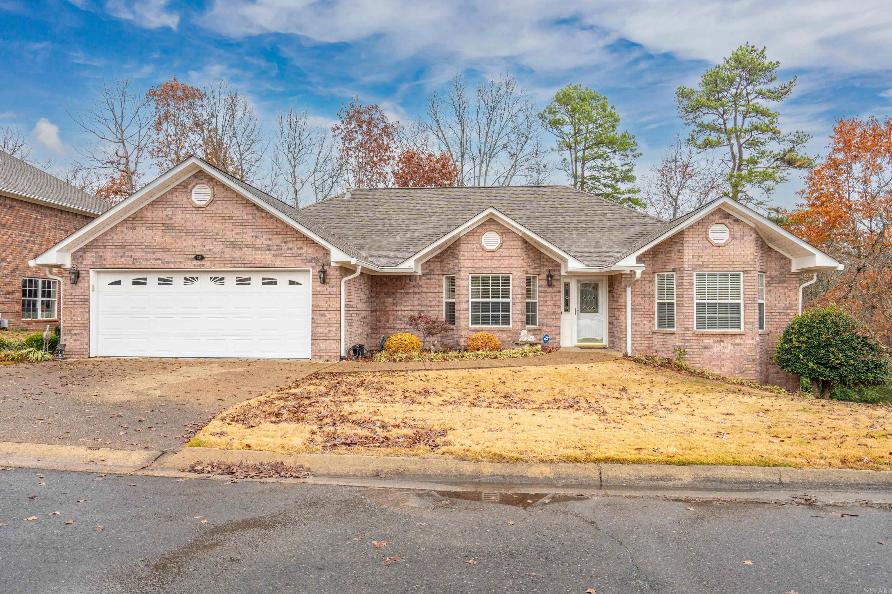 Beautifully landscaped, one level home nestled in the heart of Hot Springs, this charming home is part of a highly sought-after 55+ community, offering both convenience and comfort.  Vaulted ceilings in Living/Dining/Kitchen areas add volume and interest. Kitchen was renovated in 2019 including new cabinets, solid surface counter tops and upper-end appliances. Luxury vinyl flooring also added.  HVAC was also replaced in 2019.  Split floor plan with Primary Bedroom on one side of Great Room, 2 guest bedrooms and one bath on other side. Primary Bedroom has two walk-in closets. Primary Bath has a soaking tub, 2 sinks and separate shower.  2 bay windows on street side add charm and sophistication to the floor plan.  The view from the wood deck is of a forested area and gives one the feel of living in a treehouse.  There are two additional rooms on the lower level for a workshop, craft room, additional storage or a storm shelter if needed.  Double attached Garage with floored attic storage above it. Home is all brick with vinyl siding on soffits for low maintenance.  POA maintains the front yard. Please excuse the photos as there is currently a living estate sale in progress.