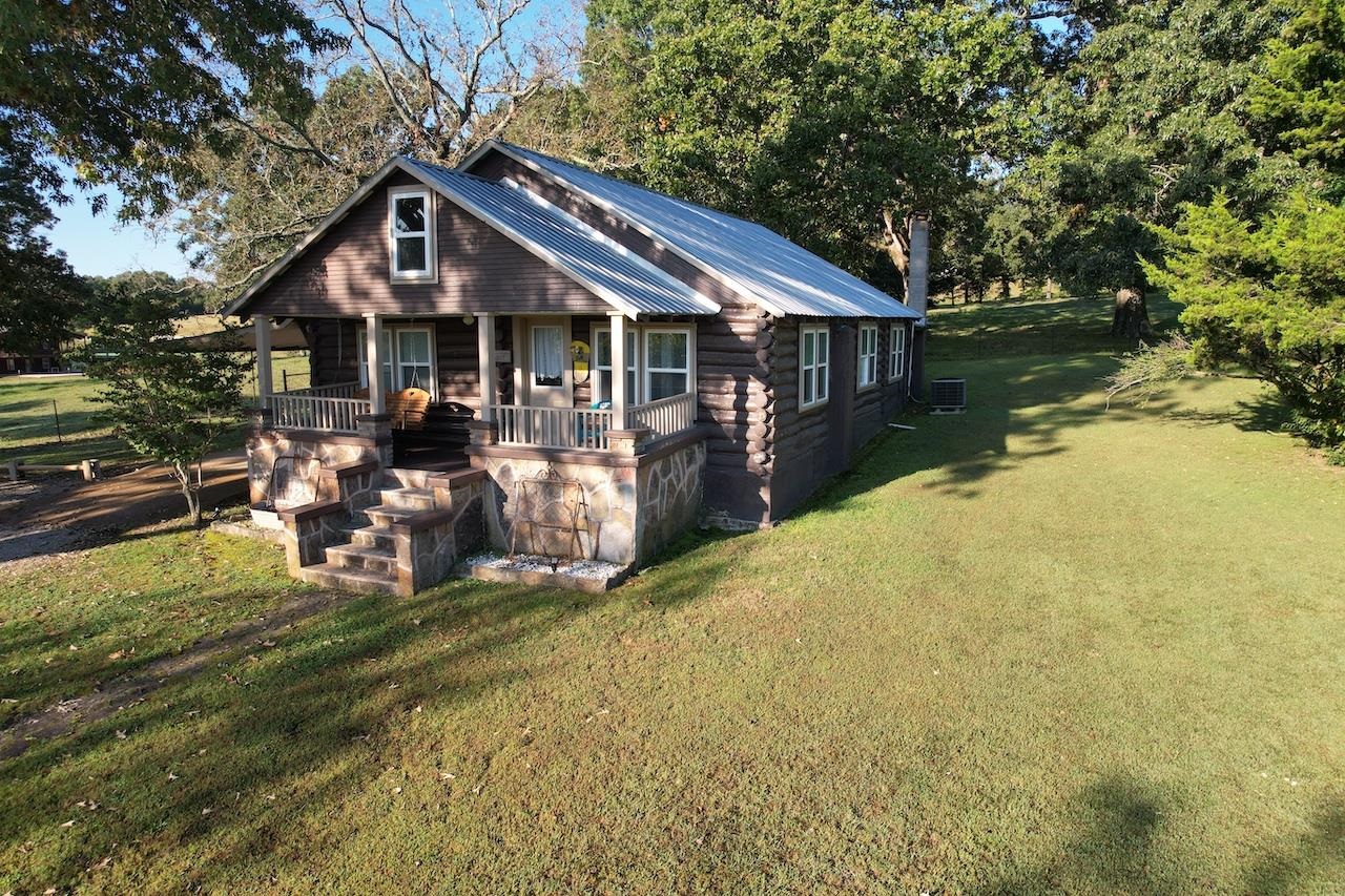 Log Cabin/Metal Roof has Shaded Pasture w/pond. 3-bedroom log cabin with a metal roof extensive remodel. Galley style kitchen includes refrigerator, glass top range, microwave and exhaust fan. Open living and dining area leave the cabin feeling larger than the 972 sq ft it is. Full bath with separate tub and walk-in shower. Utility room includes, washer/dryer unit and built-in shelving. Fresh paint and flooring throughout. Electric Heat Pump central HAVC. Covered front porch, 14x27 carport, 14x14 covered patio, 10x14 storage building. 6 perimeter fenced acres with pond and auto-waterer is rolling park-like pasture shaded by scattered heritage size Oak trees, great for your livestock.