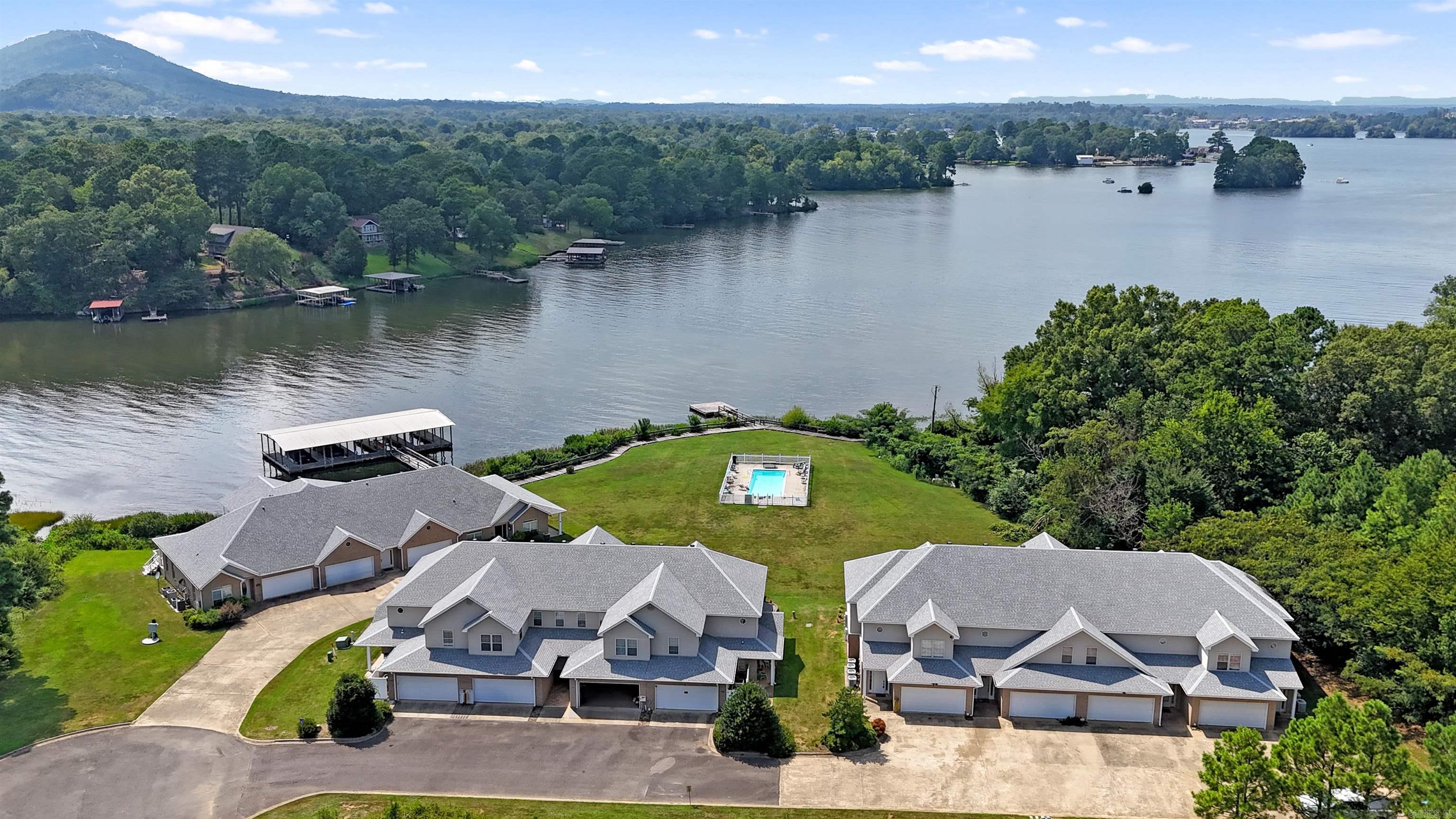 Step into LAKEFRONT living with this FULLY FURNISHED spacious townhome nestled in a serene & private setting with a dedicated 31 x 9 COVERED BOAT DOCK! The thoughtfully designed home is ideal if you're seeking a weekend escape, a full-time lakeside retreat, or a great investment opportunity. On the main level, youāll find an open-concept living/dining/kitchen area featuring a cozy fireplace, breakfast bar & French doors leading to a patio. The primary bedroom suite is conveniently located on the main floor, along with a half bath, laundry room & a 2-car garage. Upstairs, a loft overlooks the living area, creating the perfect reading or sleeping nook, a full bath & 2 bedrooms; one that features French doors that open to a covered balcony showcasing CAPTIVATING VIEWS of LAKE HAMILTON & the surrounding MOUNTAINS. Step outside and enjoy relaxing by the lakeside pool, or stroll down to the boardwalk, swim dock, or launch your boat. There's even a public boat ramp nearby making access a breeze. Currently a short-term rental that comfortably sleeps 10ā12 & offers exceptional income potential without the fuss of a permit. Pack your bags and get ready to fall in love with the waterās edge.