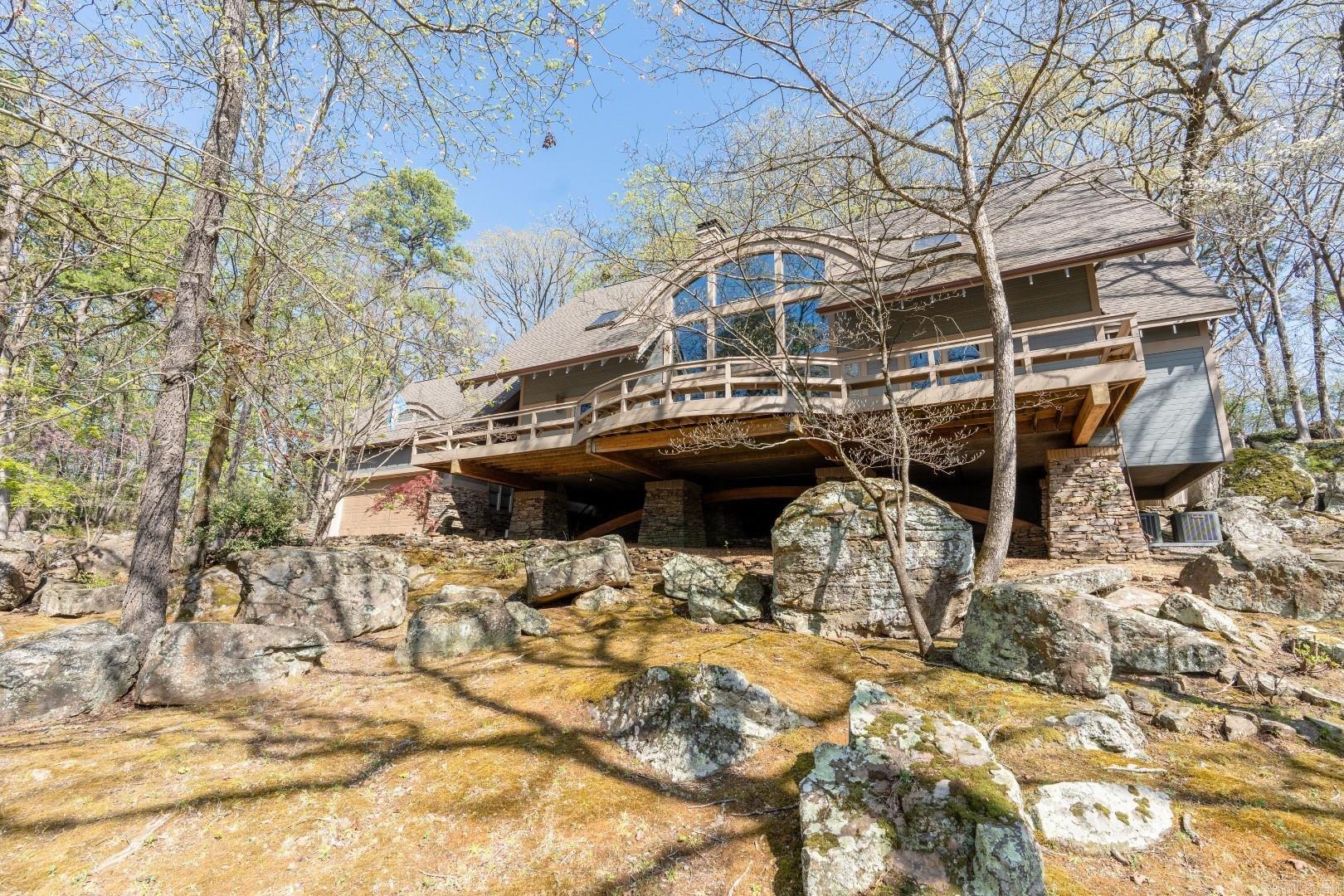 This home and its property (2 stunning boulder-filled lots) are an Eden Isle Masterpiece! Built in 1990, the foundation is not only overbuilt, but is also a work of art! Sitting in the middle of two large lots, this home features 4-bedrooms, 3.5 bathrooms, barrell (wooden) ceiling in living, a beautiful wooden staircase, lots of glass, wood floors, 2-story 2-sided stone fireplace, primary suite on the main level with very large walk-in rain shower, beautiful kitchen with granite tops, stainless built-in appliances, island with gas cooktop, icemaker and breakfast bar. Upstairs are 3 very spacious bedrooms and 2 full baths. 2-car garage, large front deck overlooking Greers Ferry Lake and a backyard that backs up to the 16th fairway of the Red Apple Championship Golf Course! The Red Apple Inn and Eden Isle Marina are just a short cart ride! An absolutely lovely property!