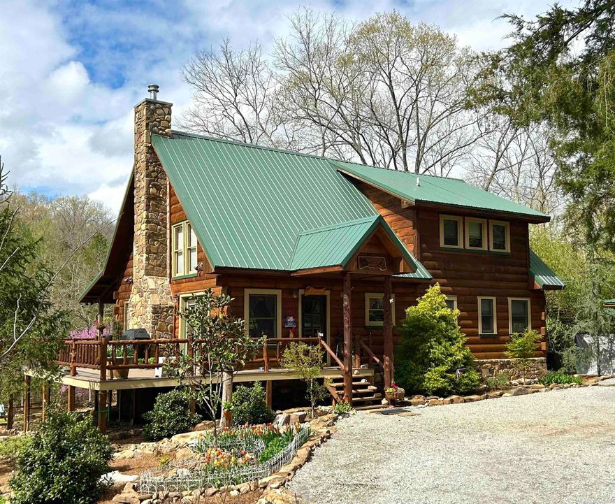 Reminiscent of the illustrations in a favorite storybook this is a home to be enjoyed through the seasons. The professionally landscaped grounds that rise above Lick Fork Creek and surround the home burst into color in the spring with blooms from redbud and dogwood trees, azaleas, tulips, and an wide assortment of other perennials. Enjoy splashing in the creek on hot summer days, roasting marshmallows on the creekside firepit in the fall, and warming by the great stone fireplace in the log house in the winter.  Located at the end of the road in the gated Lick Fork subdivision this exquisite property is both private and convenient to shopping and entertainment in Mountain View. The handsome and sturdy log house has been well maintained and boast an abundance of windows for natural light and enjoying the scenery. Downstairs is the great room with the soaring cathedral ceiling, kitchen, two bedrooms (one of which is large and and opens onto the back porch), a bath, and a laundry. Upstairs is the large loft bedroom with a generous en-suite bathroom featuring a clawfoot tub, separate shower, and double vanities. There is also a log storage building and a large dog run.  Video in links.
