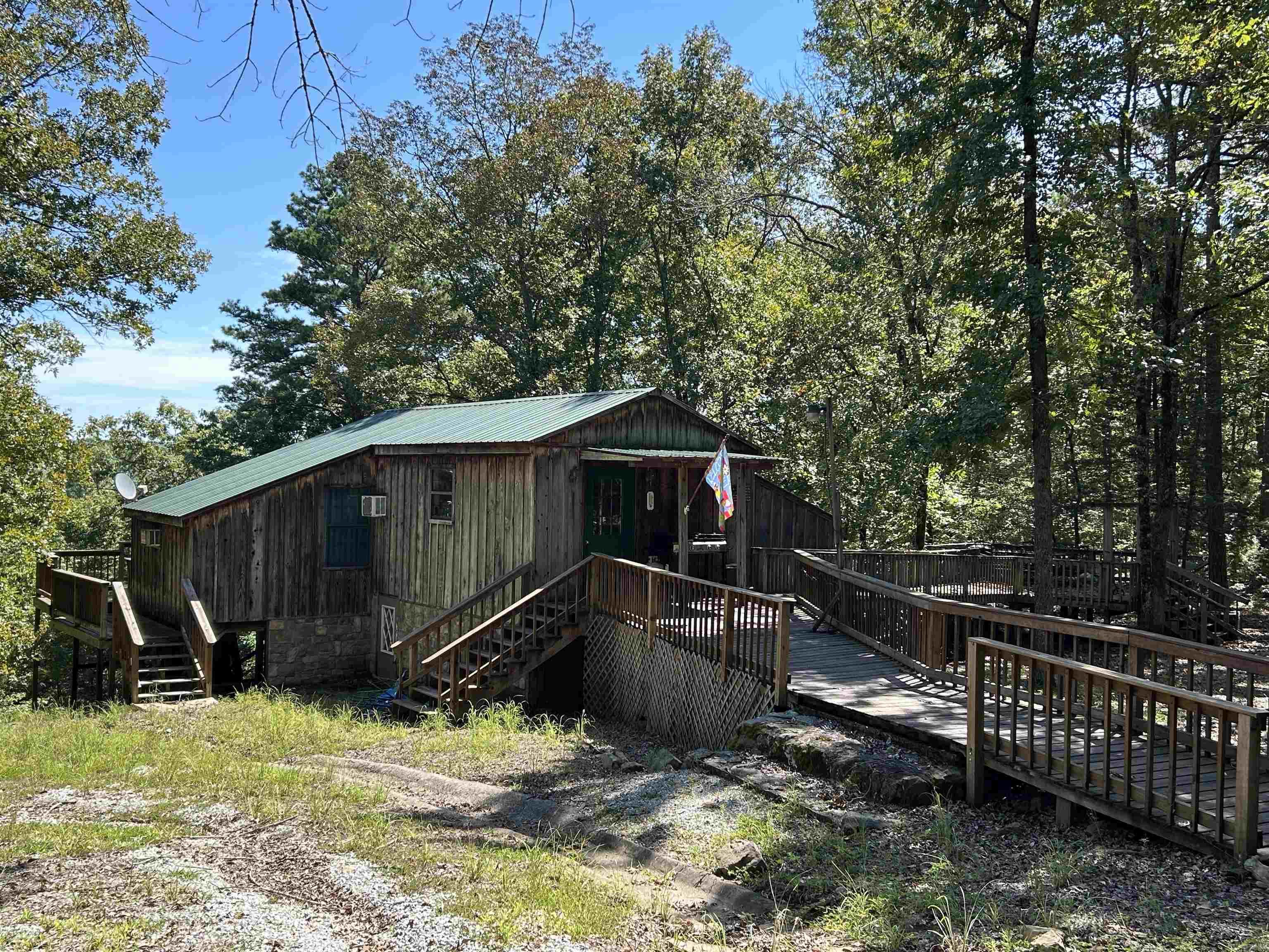 Located on a spacious lot with stunning seasonal views of Greers Ferry Lake, this charming property offers a peek of the water in summer and a breathtaking reveal of a lake island when autumn leaves fall. Surrounded by natural rock formations, the home features a large deck perfect for entertaining or soaking in the serene scenery. The lower level includes a basement room ripe for remodeling to suit your vision—ideal for a cozy retreat or extra living space. An outdoor storage shed provides ample room for lake gear, and the property’s prime location is just minutes from Frontier Canyon boat ramp, ensuring easy access to boating and lake adventures. Embrace the beauty and potential of this unique Lakeview Property!