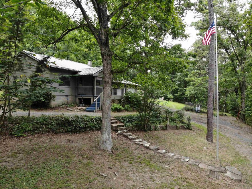 Take a leisure drive down the gravel driveway, past your pond with the beautiful rock dam, to your oasis in the woods. The home offers 1,560 sq. ft. under roof, including 867 sq. ft. of living space and a 693 sq. ft. 2-car garage/workshop. Features include 2 bedrooms, 1.5 baths, and an open kitchen/living area with all appliances conveying. There is a partial basement that includes a Fisher wood stove, storm shelter space, and plenty of storage for canned goods.  The home sits on 38 +/- acres of mostly wooded, hilly terrain with approximately 700’ of Tick Creek and a beautiful swimming/fishing hole. There is also a separate studio building that could be office, overflow room for guests, etc.  Below the studio is a barn with chicken coop and space to park your ATV and tractor.  Enjoy privacy, abundant wildlife, and year-round beauty—perfect for a full-time residence, weekend getaway, or recreational retreat.