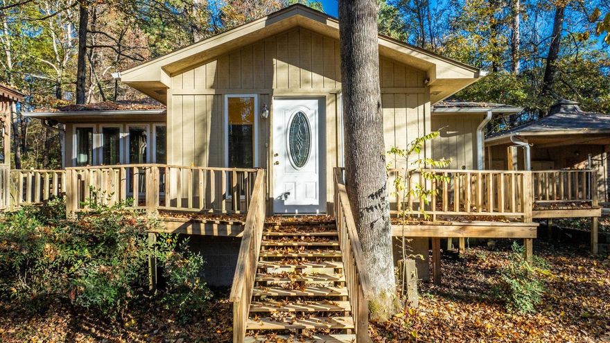 Tucked on 2.5 wooded acres, you’ll find this charming home offering the peace of a countryside retreat without giving up the convenience of being minutes from town.  Step through the front door into a welcoming sitting room — a flexible space that works beautifully as an office or dining area. From there, the home opens into a spacious living room where walls of windows fill the space with natural light and wooded views. A rock fireplace anchors the room, setting the tone for cozy evenings and slow mornings alike.  The kitchen features ample cabinetry, stainless appliances, and cheerful character, while the primary suite brings warmth with its wood-accent wall and ensuite bath with dual vanities.  Step outside and the setting takes over — a wraparound deck for morning coffee, a gazebo for evening conversations, and a powered barn ready for projects or storage. An 8×12 tool shed and storm shelter add function and peace of mind. Recent updates, including a new roof (2021) and Wilson windows, ensure comfort for years to come.  Blending comfort, character, and connection to nature, this home is where life slows down — and at 18 Sheila Lane, every day feels a little more like a getaway.