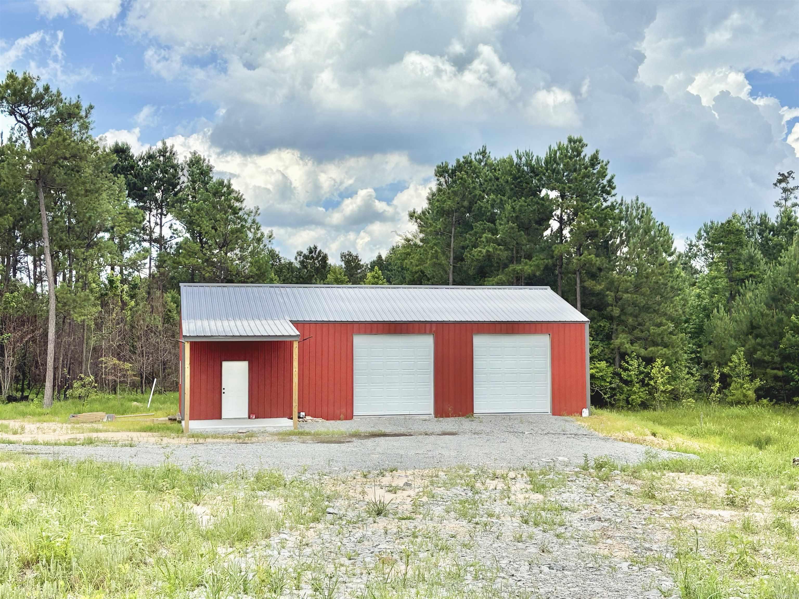 Need a place to build your forever home? Here is the perfect spot, tucked back off the road. There is a shop already in place, you just need plans for your new home! Property Overview: The driveway is already in place with two installed culverts. Power has been brought onto the property with lines run all the way in, including a temporary pole and meter. A 1,200-foot water line (not yet installed) is on site, and a water meter is already in place—just awaiting connection by the new owner. The house site has been cleared and leveled, ready for construction. Shop Details: The shop is a 30x50 building with 12-foot walls, featuring two 10-foot roll-up doors and one walk-through door. It includes finished concrete flooring throughout. The interior is framed for a small bathroom with sink & shower. While not yet fully plumbed, the materials are on site. Materials will convey-sold as is. To be finished by new owner.