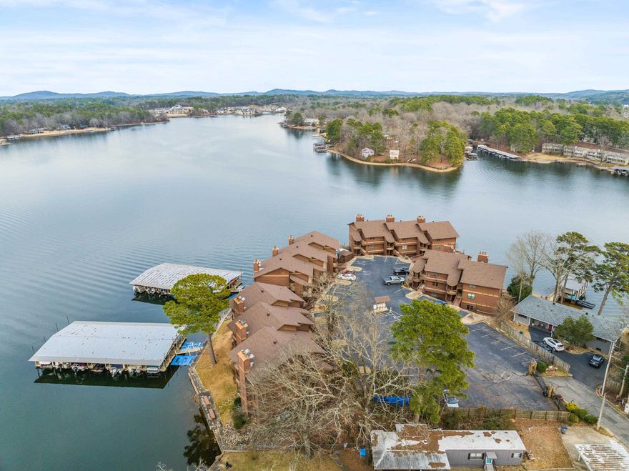 This beautifully remodeled lakefront condo sits on the point of a peninsula, offering some of the best views in Hot Springs! Enjoy your morning coffee on the private balcony while soaking in the serene lake scenery, or unwind in the evening with a spectacular sunset. Located off HWY 7 South, it's close to everything Hot Springs has to offer. Sold fully furnished- including all furnishings, linens, and dishes- this turnkey condo is perfect for a seamless move in or vacation retreat. Inside you'll find stylish tile flooring that looks like wood, combining durability with warmth and charm. Convenience is key with a dedicated parking space right in front of this walk in level unit-no steps required! Additional amenities include a private covered boat slip, gated entrance, and community pool. Plus, with no nightly rentals allowed, you'll enjoy a peaceful atmosphere. Call today to own a slice of lakefront paradise!