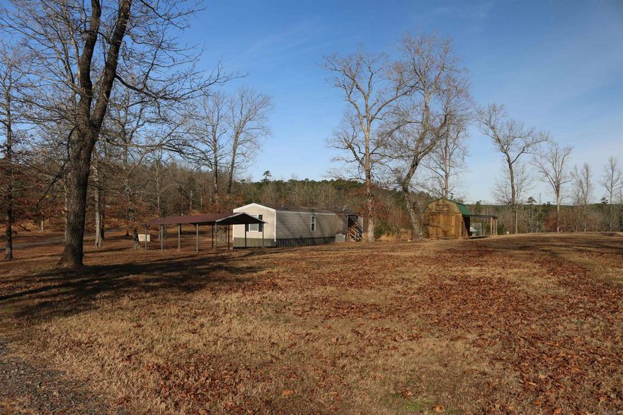 This tract is truly something to look at! A newer mobile home sits on roughly 6 +/- acres out in the country. The mountain views are truly remarkable here. The 2 bedroom, 2 bath mobile home is move-in ready with a new washer and dryer hooked up, a new refrigerator, and a cook stove that stays with the purchase. It has power and a water well with a well house with a new pump and filter system that is established, making it easy to get moved in. Along with the 800-gallon septic tank that is already put in place as well.  The metal carport and outbuilding in place are perfect for vehicle protection and storage for whatever you need to keep out of the weather. Enjoy your morning coffee sitting beside the stocked pond, watching the sunrise on the beautiful Ouachita Mountains. If you are looking for the perfect getaway from the loud, busy day-to-day life, look no further.