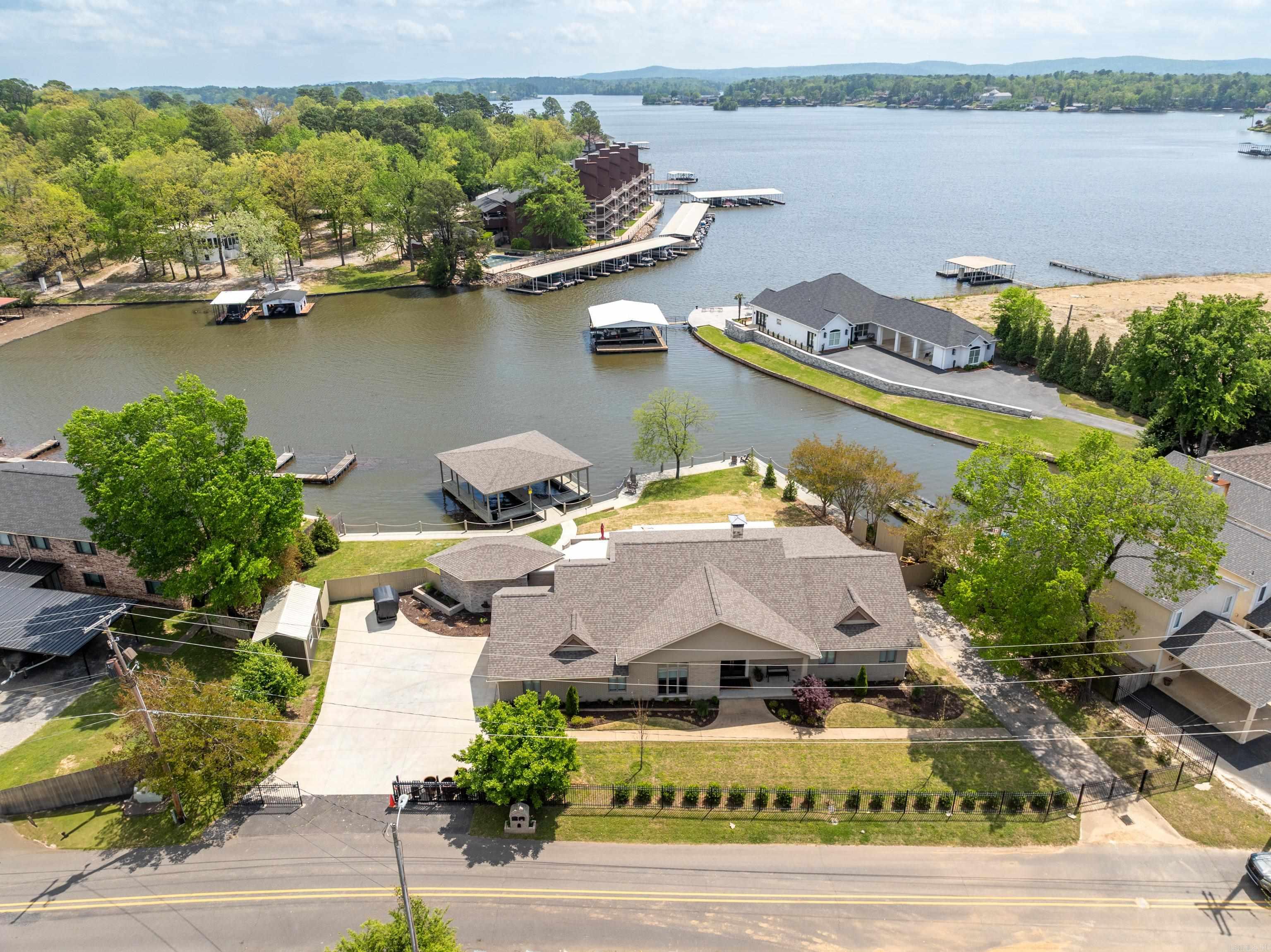 LAKEFRONT PARADISE ON LAKE HAMILTON- Welcome to your dream retreat on beautiful Lake Hamilton. Nestled in the highly sought-after 7 South area, this stunning 2-bedroom, 2.5-bathroom, 2,463 sq ft home offers the ultimate lakefront lifestyle — move-in ready. From the moment you enter through the gated entrance, you'll be captivated by the serene atmosphere, breathtaking lake and pool views, and the convenience of being just minutes from top-rated restaurants, shopping, and entertainment. This single-level home was designed for effortless living and unforgettable entertaining. Relax or host guests in the remarkable outdoor entertainment area, complete with outdoor kitchen and a built-in bar that seats eight. Take a dip in the newly added in-ground pool, or stroll down to your covered two-slip boat dock for spontaneous lake adventures. New professional landscaping enhances the beauty and privacy of the property, while multiple patio areas offer ideal spots for lounging, dining, and soaking in the waterfront scenery. Perfect as a full-time residence, luxurious vacation home or investment property.