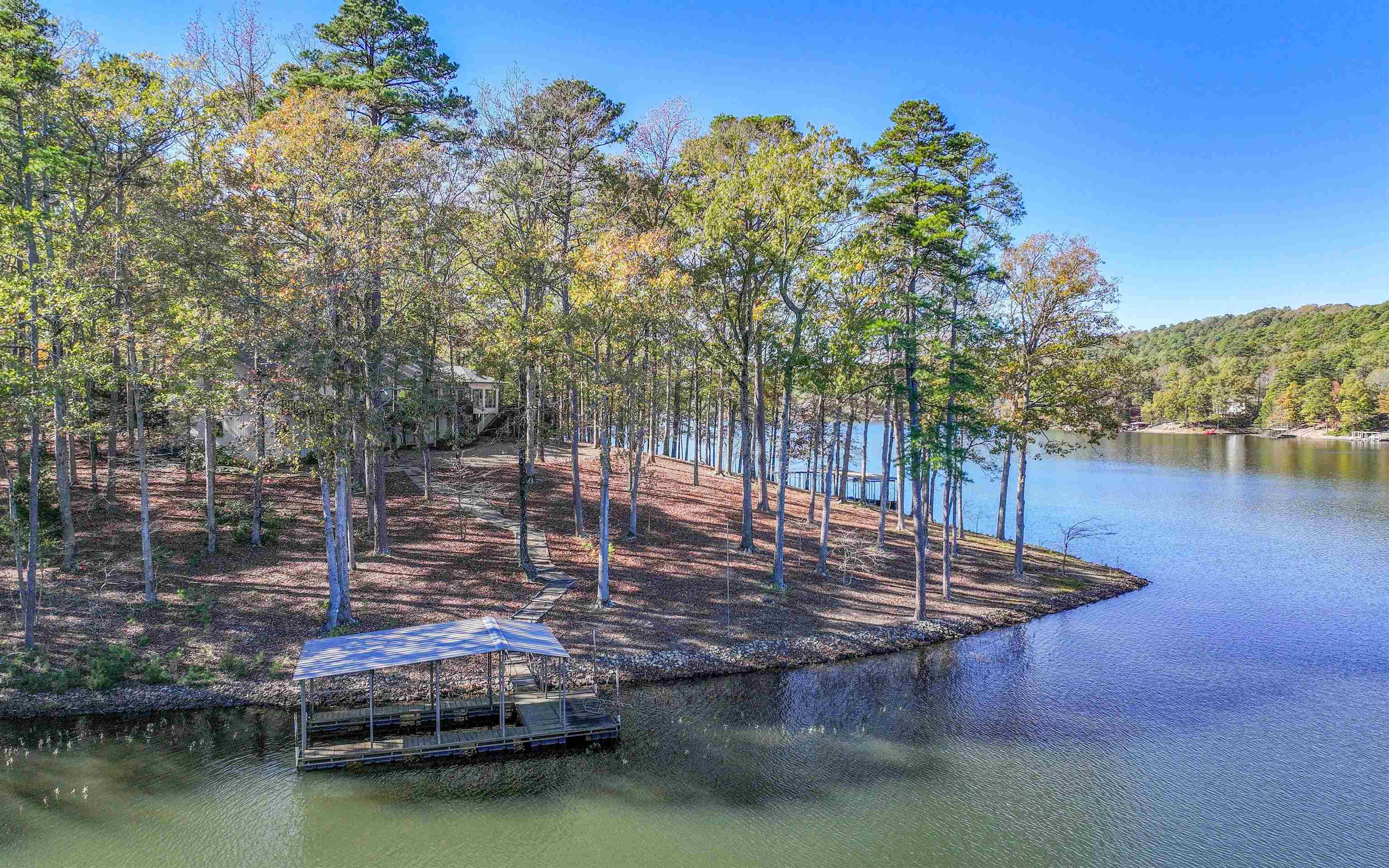 WATERFRONT 1.81 Acres with 399' on the Point on Lake Cortez! This PREMIUM lot is a RARE find with 180 degree Views of the Water! 4,671 total square feet with 3,293 on the Main Level! The Circle Drive brings you to this "Estate in the Trees" where you can enjoy the Privacy of Nature! This home boasts a New Roof and Gutters, and Newer ('22&'23 -two of three- HVAC Units + '23 Water Heater). Enter the Large Foyer and immediately see the Wall of Windows overlooking the Lake! Cathedral Ceilings with Open-beams add to the Craftsman Style, as does the Rock Gas Fireplace! The Granite Island Kitchen offers a Glass Tile Backsplash, Jenn-Air Range, Under-cabinet Lighting, Bright Skylight, Hardwood Floors, and a Wet Bar! Open the Pocket Door to enjoy Formal Dining in the Dining Room with Tray Ceiling, or pass-through the Kitchen to the Eating Area that adjoins the Arkansas Rm with Windows on 3 Sides Overlooking the Lake & Floating Dock! An Entertainment-sized Deck across the back of the home brings nature to your Living Area or BBQ! The Primary Bedroom boasts His/Her Vanities and Walk-in Closets, sharing the Jetted Tub! 2Beds+Den (or 3Beds) upstairs + 2 more Beds and a HUGE storage/Rec Rm down!