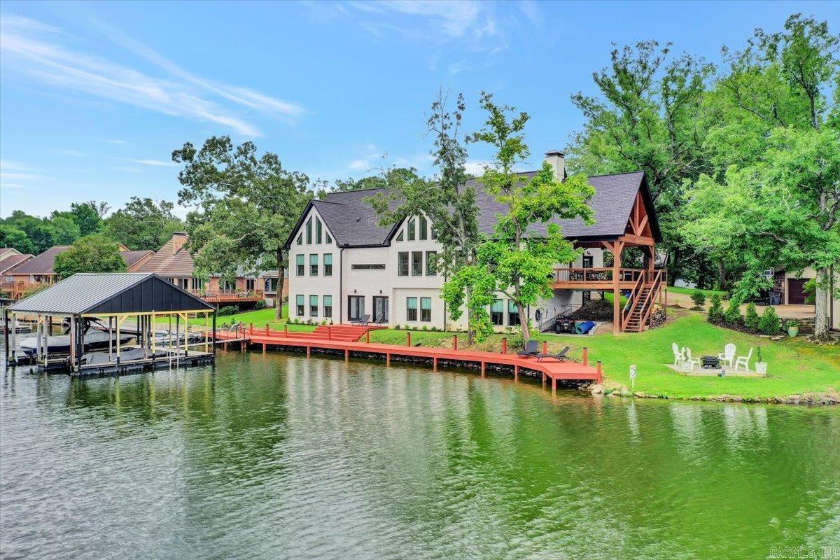 Welcome to this luxurious waterfront home located at 112 Waters Edge Cove on beautiful Lake Hamilton.This custom home is strategically placed on a pie shaped lot with 190' of lake frontage.An expansive boardwalk wraps around the side of the lot so that the double boat slip is positioned out of the wake with year-round water. Main level you will find the master suite and an inviting office boasting extensive built-ins, the kitchen and dining area and 2 half baths.A bonus room and 3 bedrooms each with private baths are located on the lower level all with lake views. Convenience of laundry on each level. An added bonus is the vaulted finished upstairs currently a gym, has the versatility to accommodate many needs. Approximately 400 sq ft of vaulted open space which is currently not heated but is energy efficient with the blown in solid insulation in the ceiling and portable a/c. Sleek and modern design along with quality construction and energy efficient features such as geothermal heat and air, 6" exterior walls, this home a must see if you are looking for luxury lake living.Water depth at dock is 8'8".