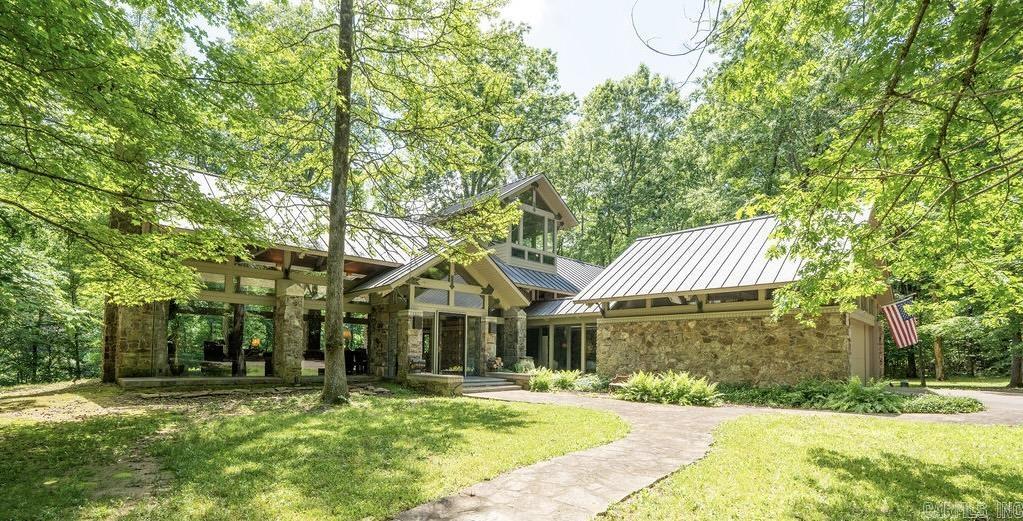 Located on the bank of Little Red River (home of the world record wild brown trout) in the Ozark Mountain foothills is an all glass mid century style home with spaces for solitude and socializing. Find total privacy on 12.9 wooded acres with approximately 700 feet of river frontage. The floor to ceiling glass walls provide a window to nature as deer, wild turkeys, foxes and others visit the surroundings daily. The gourmet kitchen opens to the great room with its large fireplace and views of the outdoors. The primary bedroom suite has two private baths, a fireplace , large walk-in closet, private courtyard. The second floor has a spacious guest bedroom, a bunk room with built-ins, and an exercise room hidden behind a bookshelf wall. The crow's nest office is above it all with views in all directions. A short walk to the 2 stall boat dock takes you to world class fishing for rainbow, brook, cutthroat and wild brown trout! A conservation easement across the river ensures unobstructed views of the natural setting in perpetuity. Designed by award winning architect Gene Levy with Cromwell Architects Engineers, custom built by Roberson Builders, everything about this home is remarkable.
