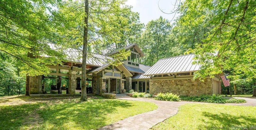Located on the bank of Little Red River (home of the world record wild brown trout) in the Ozark Mountain foothills is an all glass mid century style home with spaces for solitude and socializing. Find total privacy on 12.9 wooded acres with approximately 700 feet of river frontage. The floor to ceiling glass walls provide a window to nature as deer, wild turkeys, foxes and others visit the surroundings daily. The gourmet kitchen opens to the great room with its large fireplace and views of the outdoors. The primary bedroom suite has two private baths, a fireplace , large walk-in closet, private courtyard. The second floor has a spacious guest bedroom, a bunk room with  built-ins, and an exercise room hidden behind a bookshelf wall. The crow's nest office is above it all with views in all directions. A short walk to the 2 stall boat dock takes you to world class fishing for rainbow, brook, cutthroat and wild brown trout! A conservation easement across the river ensures unobstructed views of the natural setting in perpetuity. Designed by award winning architect Gene Levy with Cromwell Architects Engineers, custom built by Roberson Builders, everything about this home is remarkable.