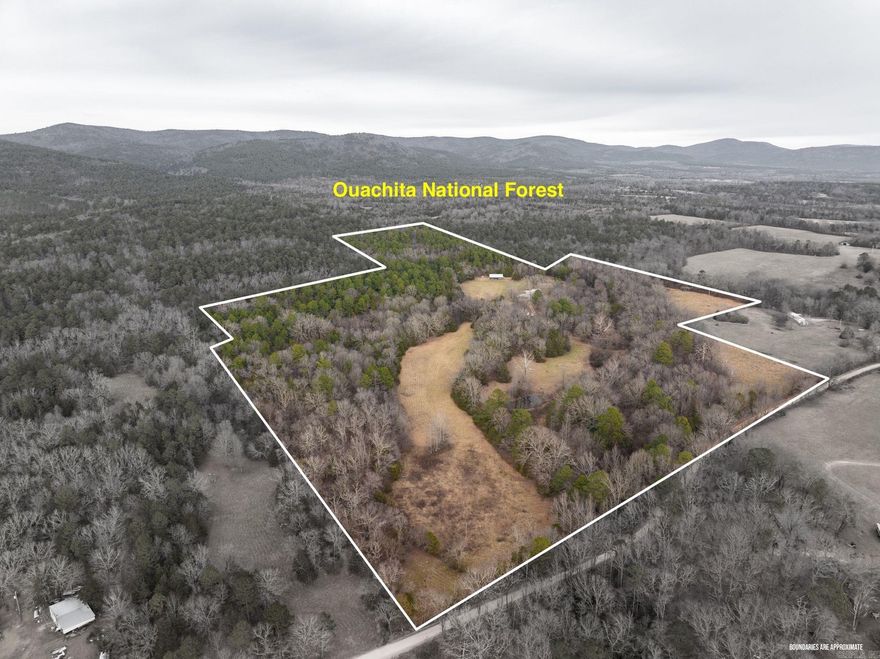Tucked away on 50± scenic acres backing directly to the Ouachita National Forest, this private retreat offers peace, space, and a true connection to nature. With approximately 3,700 sf, the home is filled with natural light from expansive windows showcasing ever-changing forest views. The layout includes 4 bedrooms and 3.5 baths. Upstairs features two bedrooms with solid hardwood flooring, including a serene primary suite with a private balcony—perfect for morning coffee and quiet views. Downstairs offers two additional bedrooms with tile flooring, ideal for guests or multi-use living. Tile baths throughout provide durability and easy maintenance. The spacious kitchen features black granite countertops, abundant prep space, and a large island with ample seating—ideal for gathering. Neutral paint tones create a warm, inviting backdrop ready for your personal touch. Multiple flex spaces accommodate a home office, game room, or media room. Outside, enjoy direct access to hiking, biking, waterfalls, wildlife, and more within the Ouachita National Forest. A 30x50 shop with 13x50 lean-to adds valuable workspace and storage. Perfect as a full-time home, weekend escape, or vacation rent